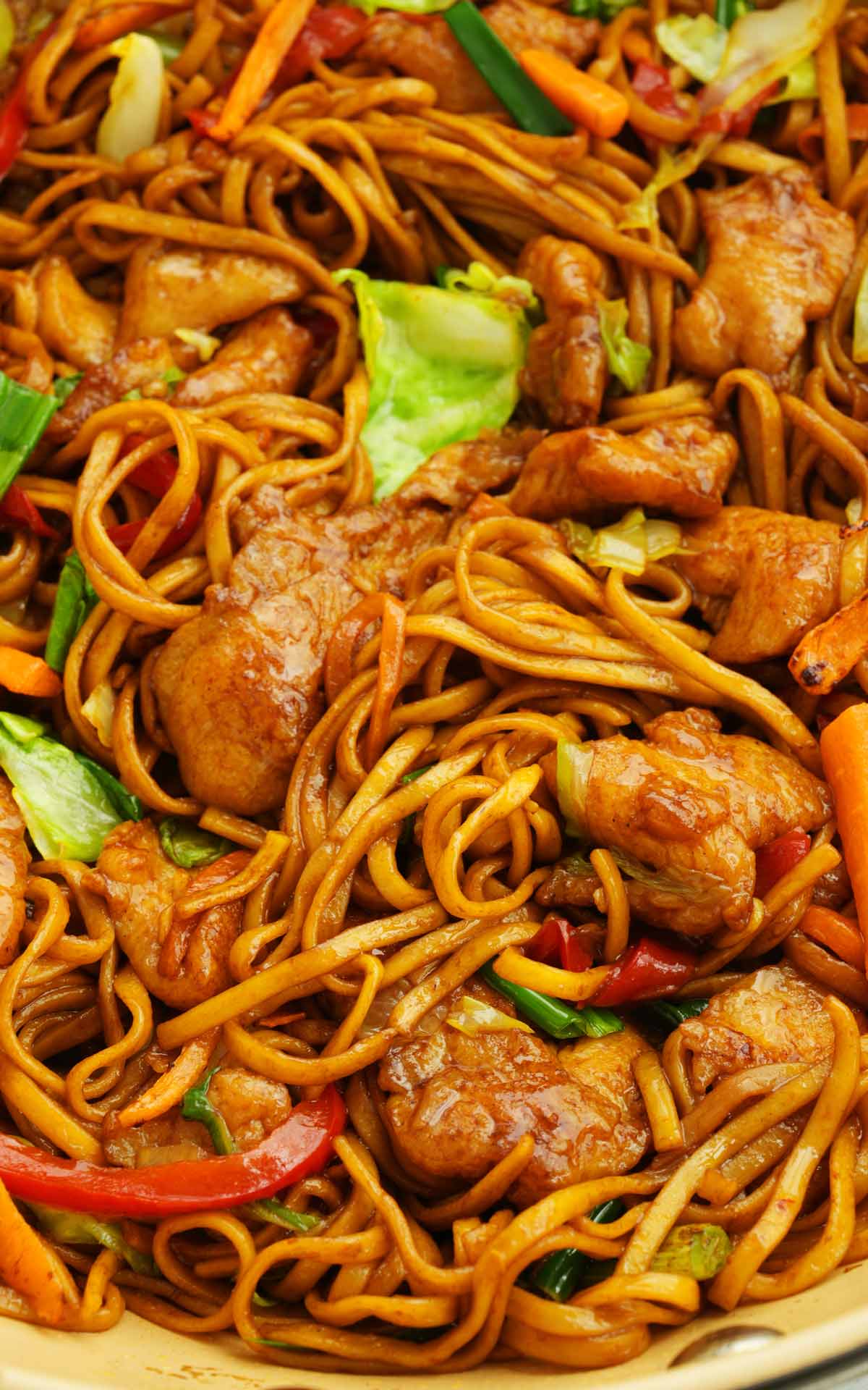 A large wok containing fried chow mein noodles with chicken, and vegetables. 
