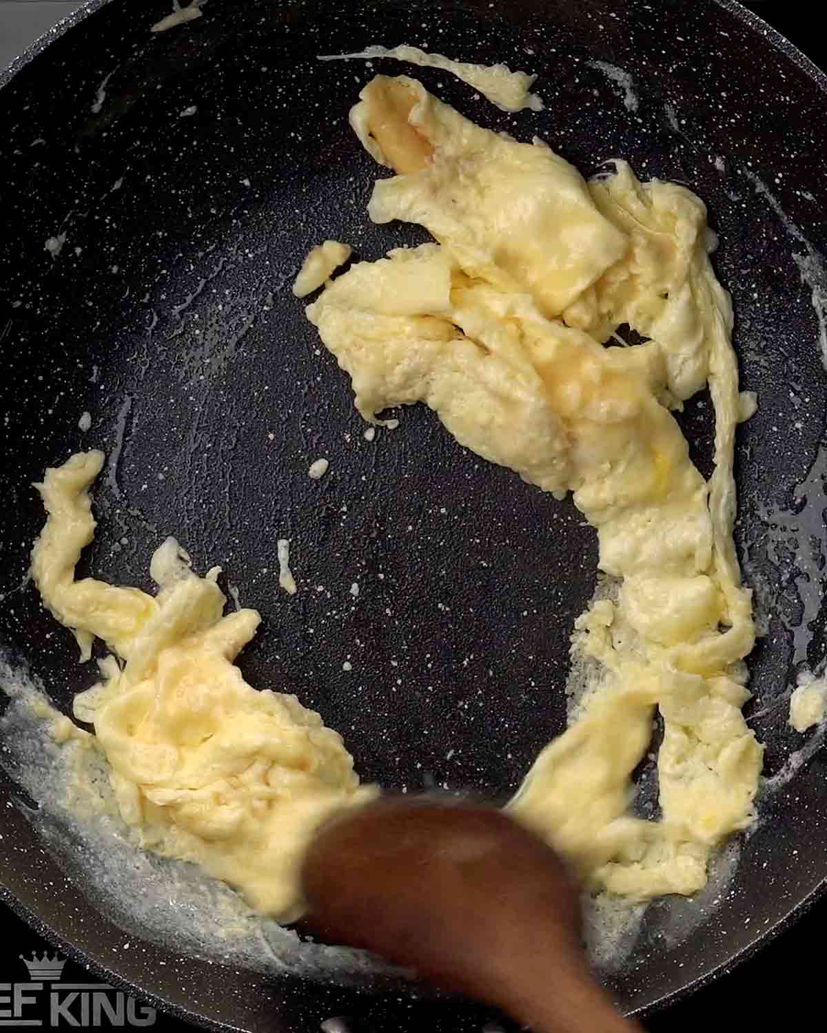 A picture of stir frying egg in a black wok.