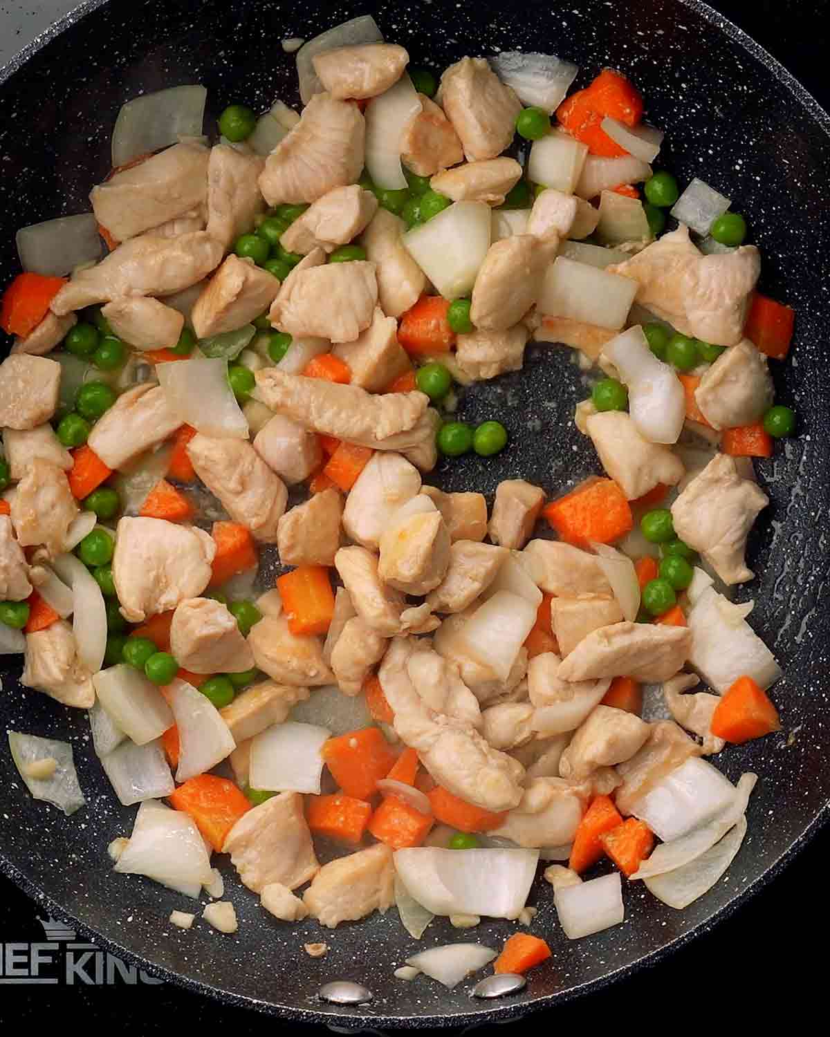 An image of stir fried chicken, and vegetables in a wok.