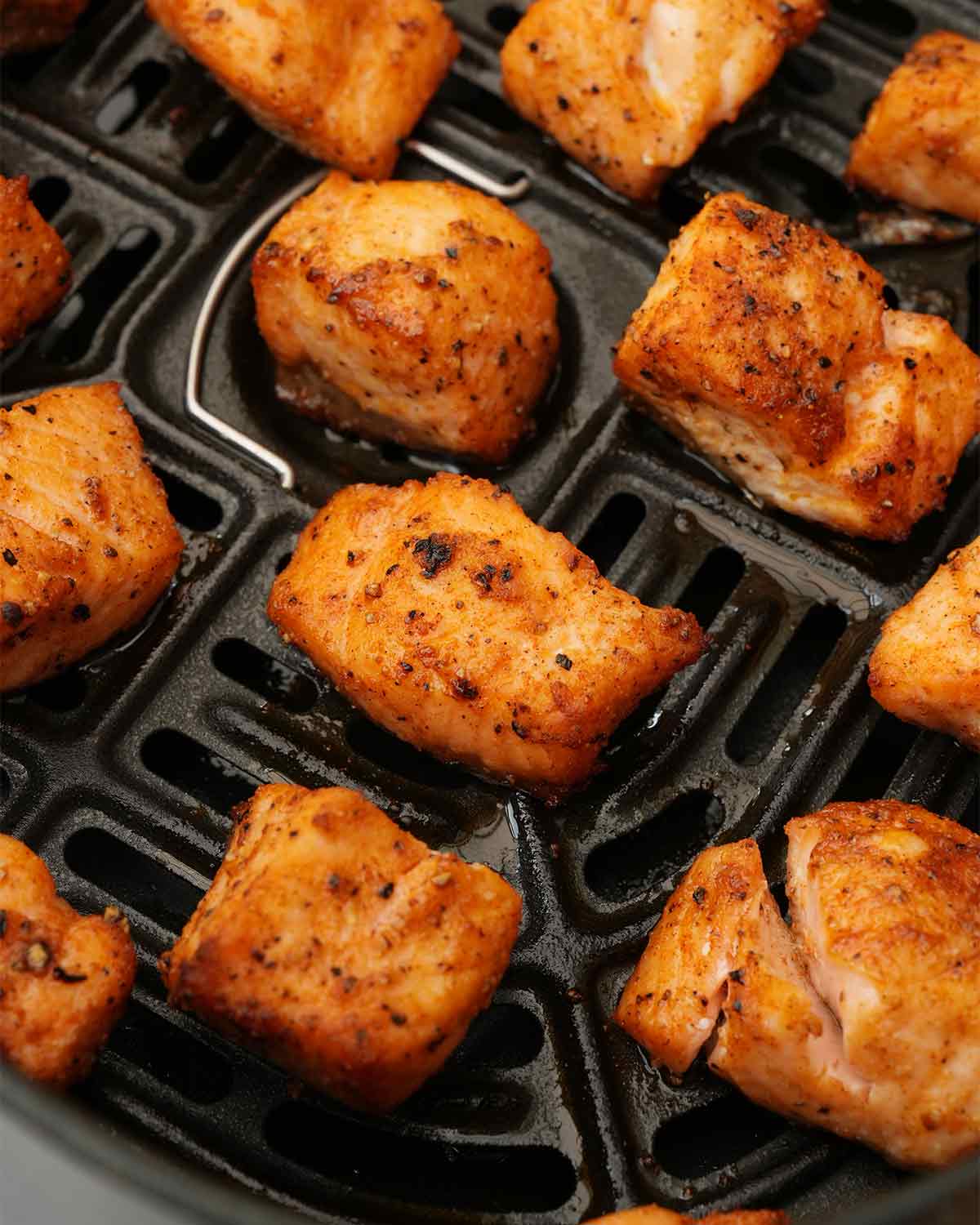 A picture of golden fried salmon pieces on the air-fryer rack.