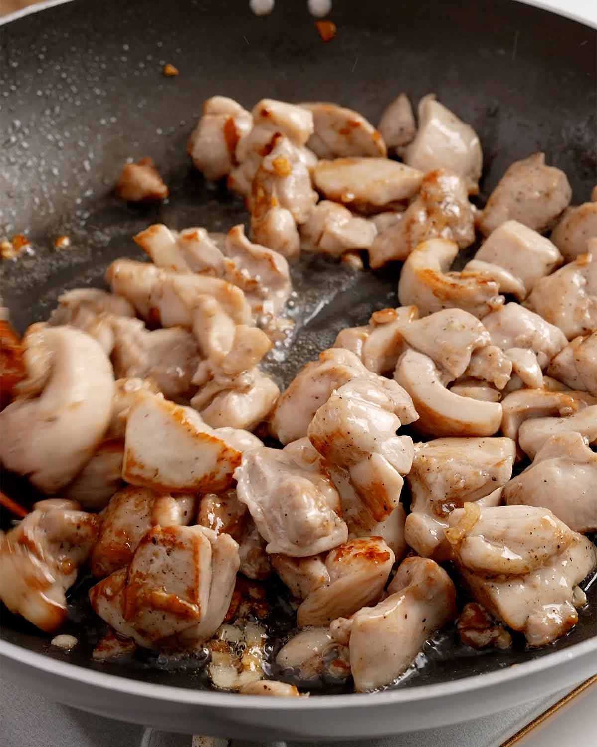 A picture of stir-fried chicken in a large black pan.