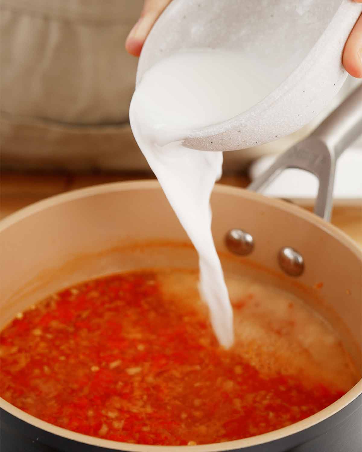 A picture of pouring cornstarch slurry into the sauce pot. 