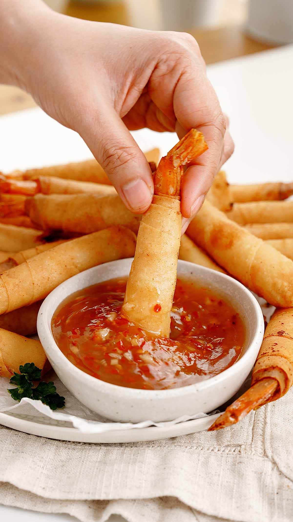 An image of fried shrimp spring rolls dipped in a sweet chilli sauce. 