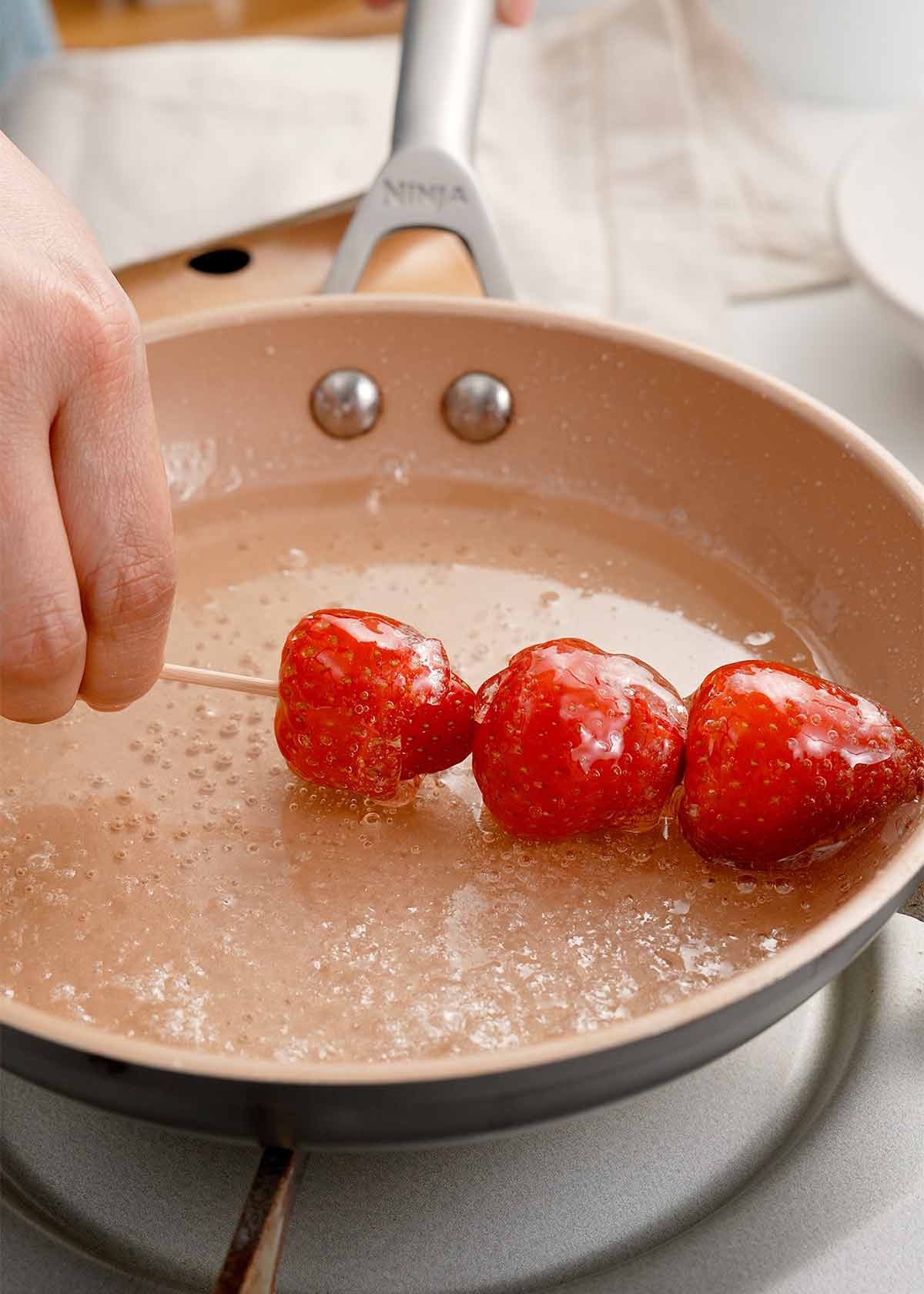 Dipping fruit skewers in the sugar syrup.