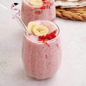 A picture of a glass containing creamy thick pink colour strawberry and banana milkshake.
