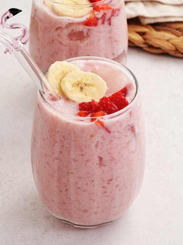 A picture of a glass containing creamy thick pink colour strawberry and banana milkshake.