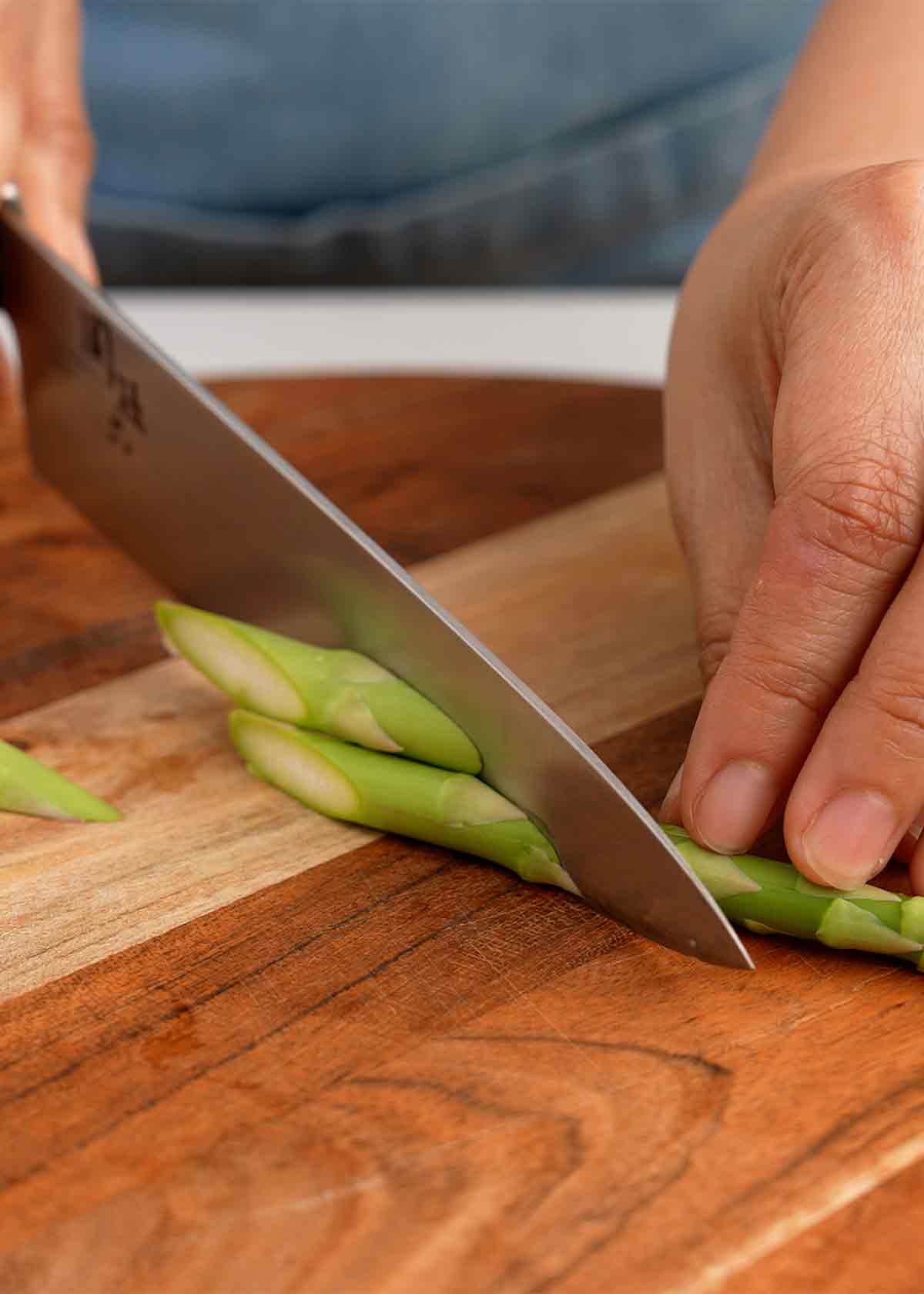 An image showing how to slice asparagus before stir frying it. 