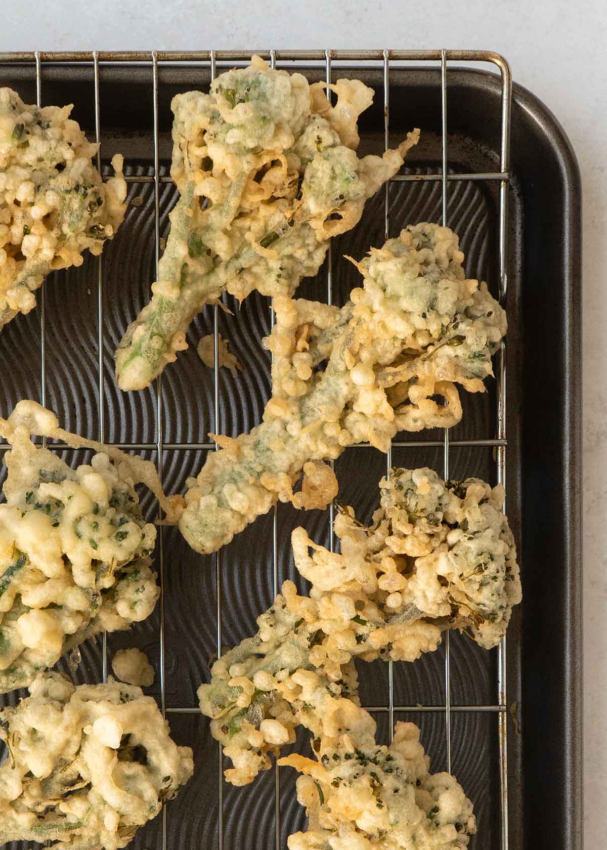 Fried broccoli bites displayed on the cooling wire rack.