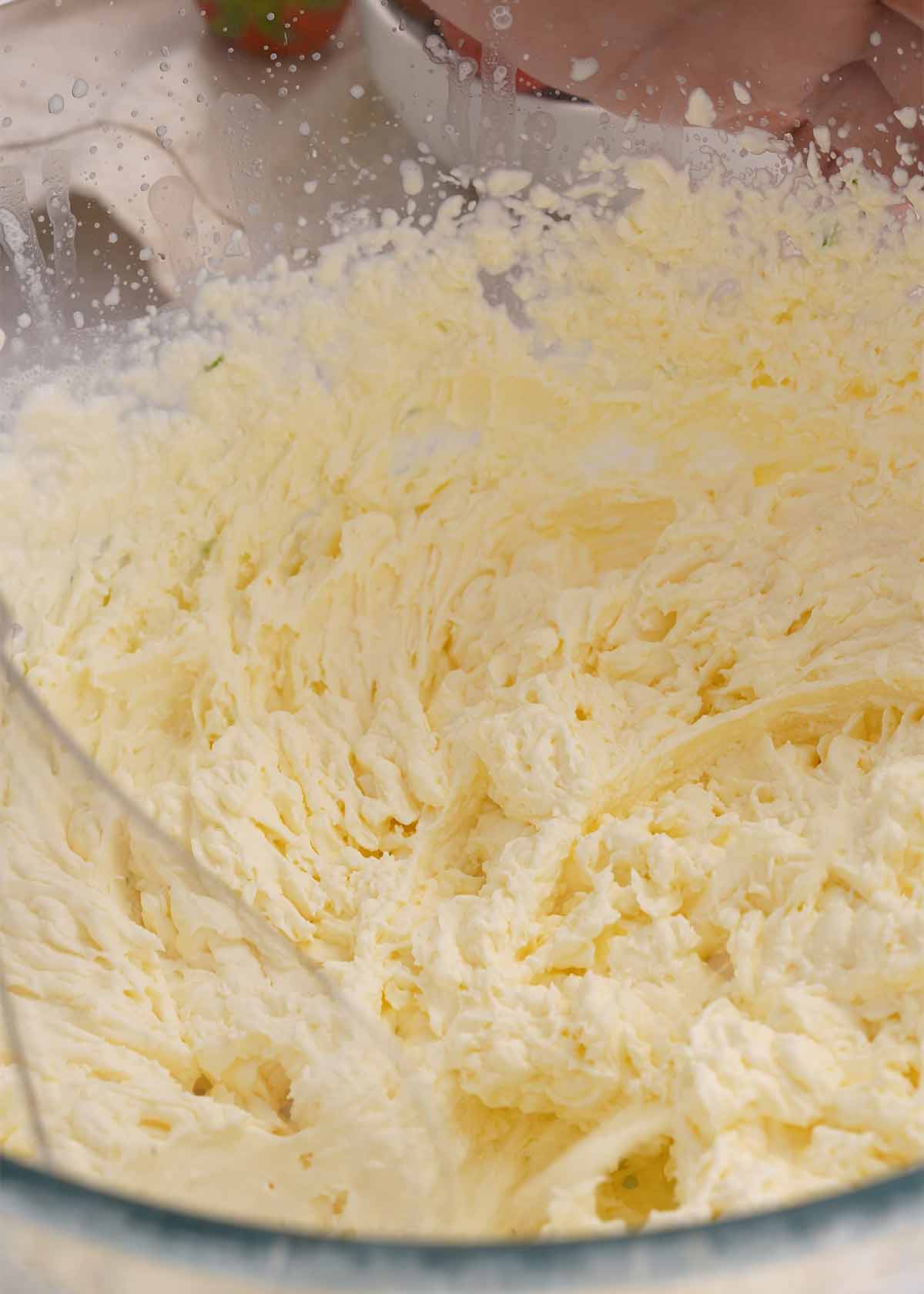 A transparent mixing bowl containing whipped cream.