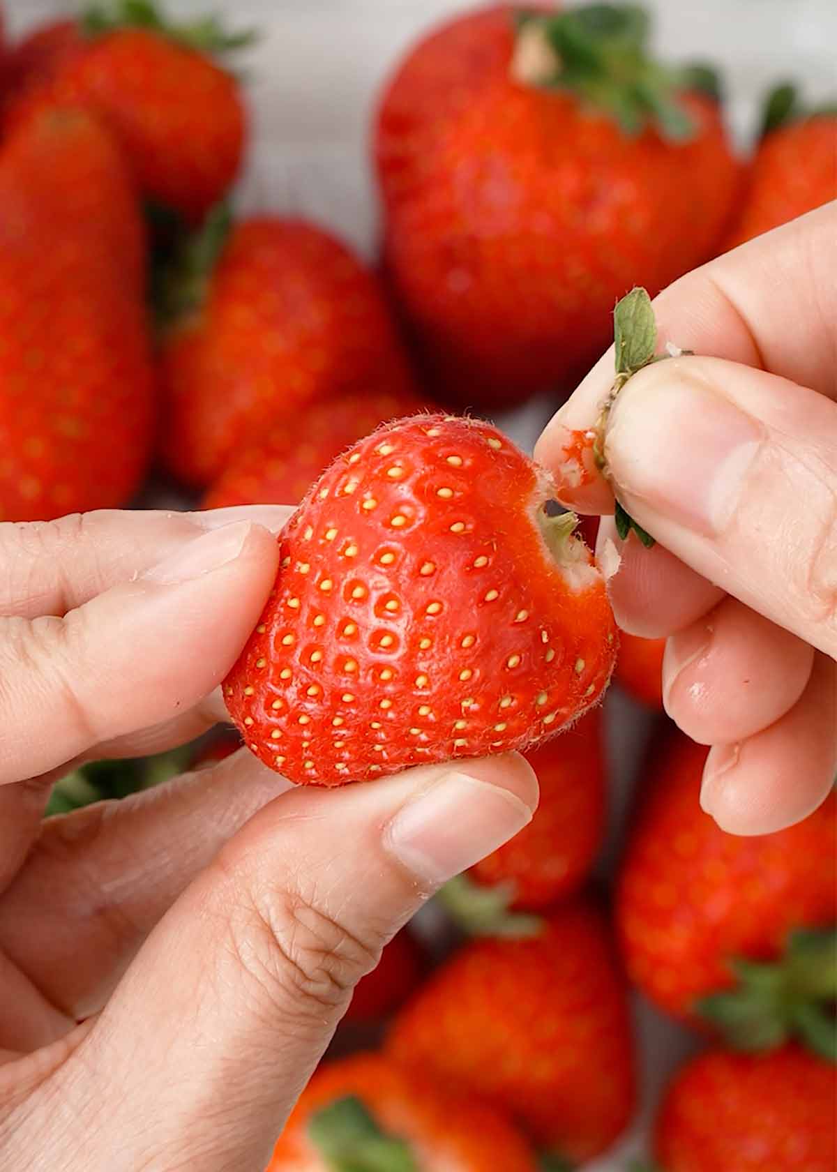 An image showing how to remove a green strawberry top.