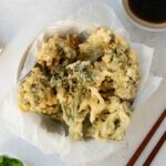A white bowl containing fried tempura broccoli bites.