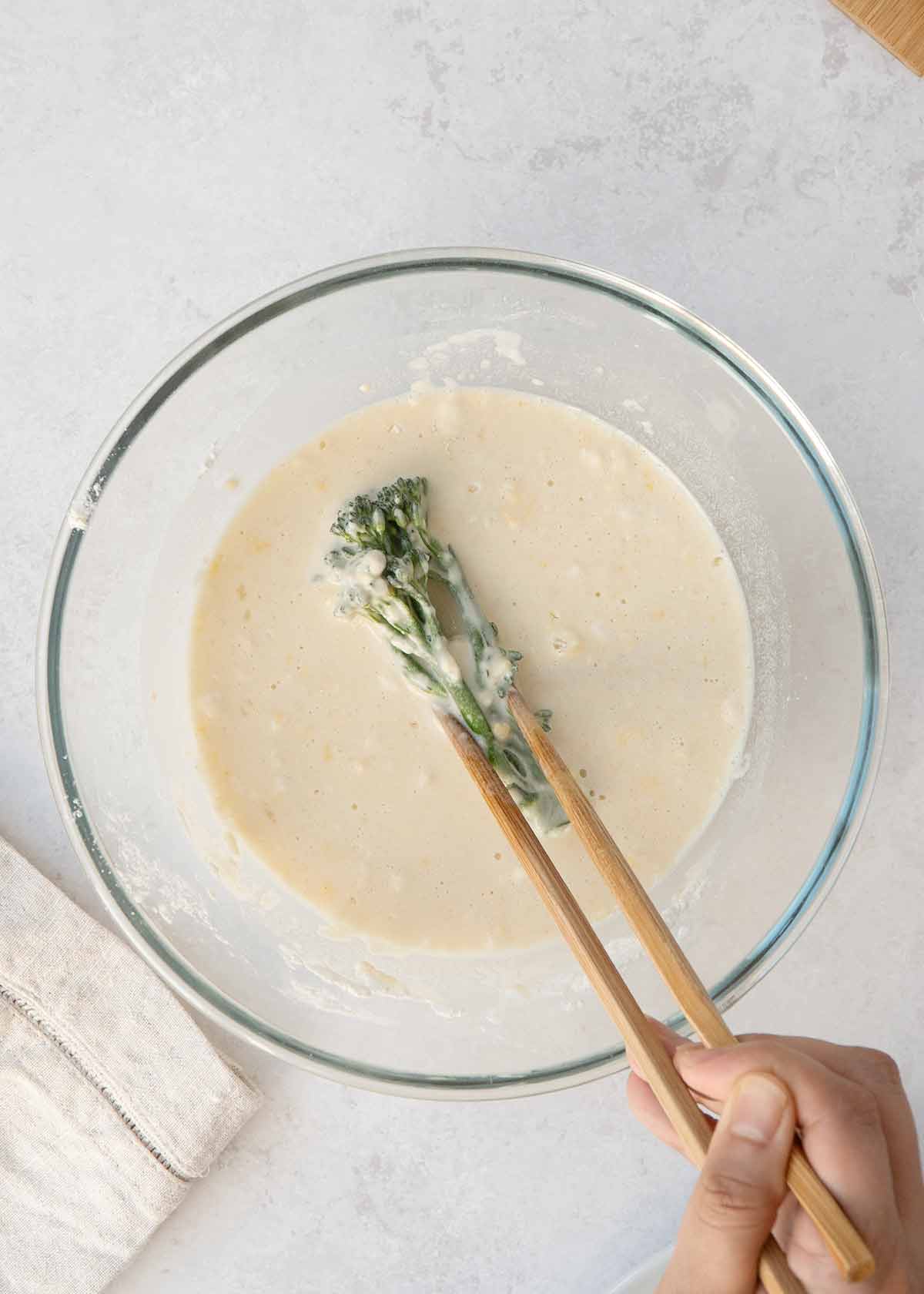 Dipping the broccoli piece in the large bowl of tempura batter mix.