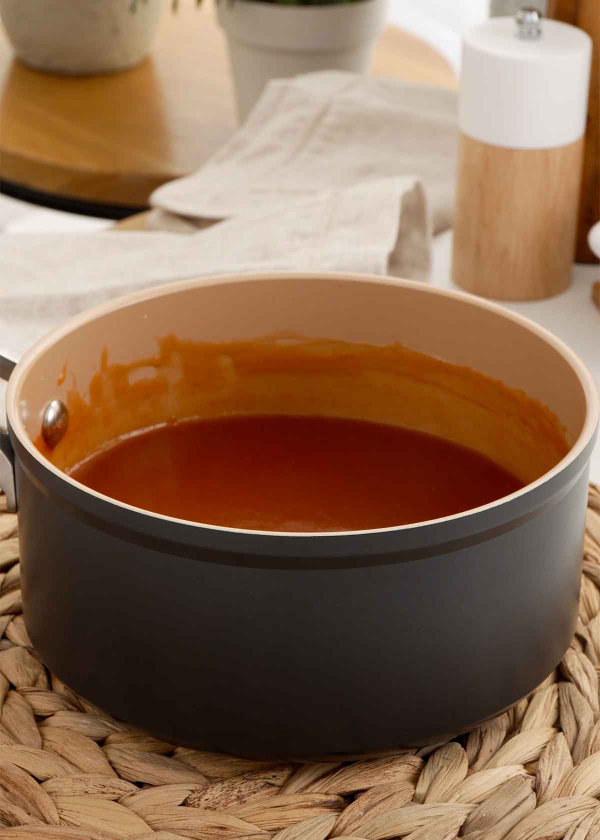 A picture of cooling down the sweet sour sauce pot placed on the rattan table mat.