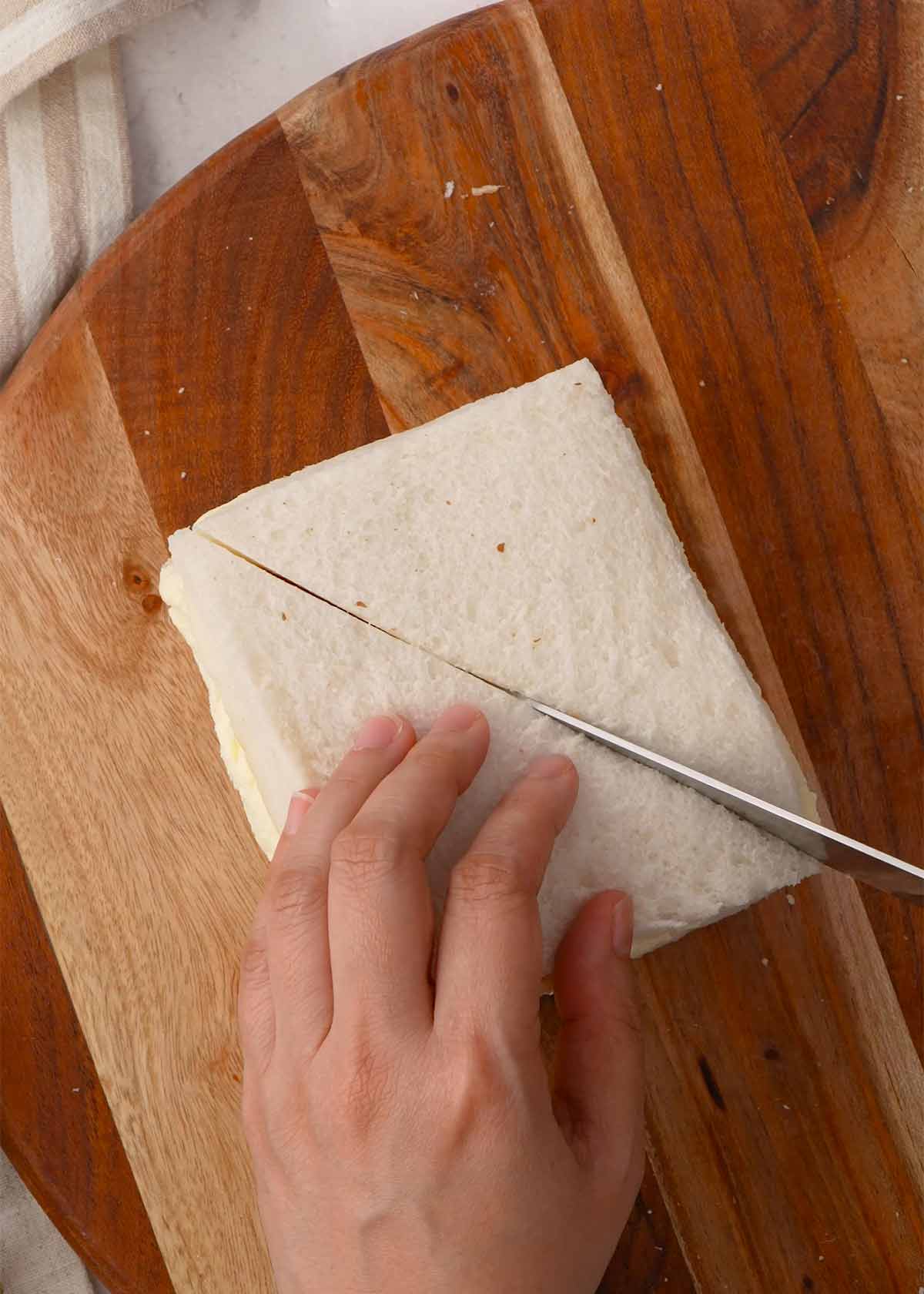 An image of cutting the square white bread diagonally into two triangles.