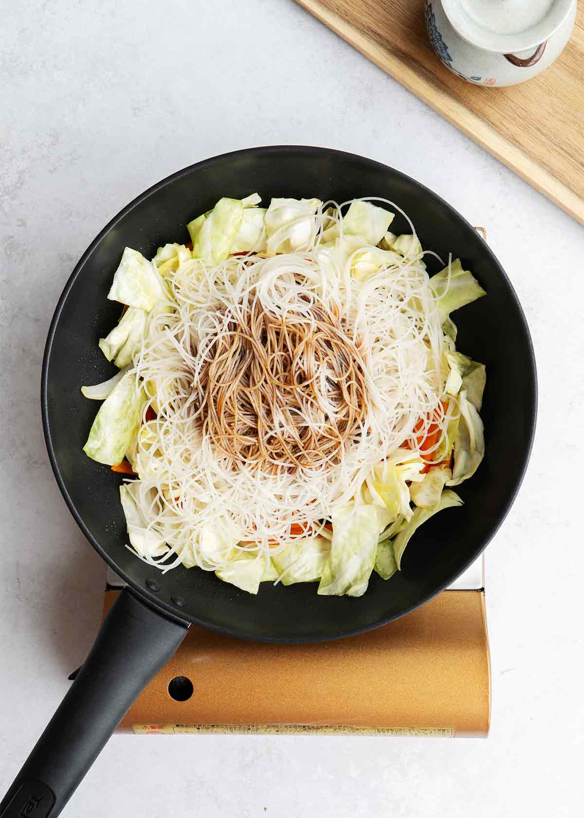 An image showing how to pour sauce to the rice vermicelli and vegetables.