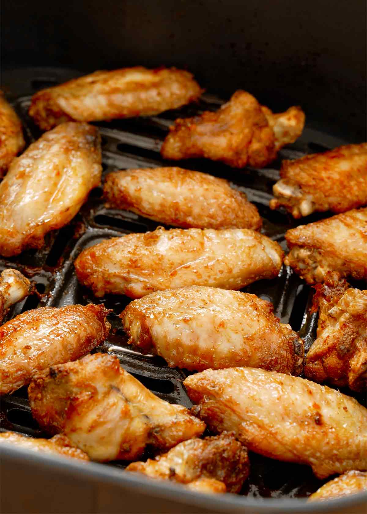 Fried golden colour chicken wings displayed on a black air-fryer rack.