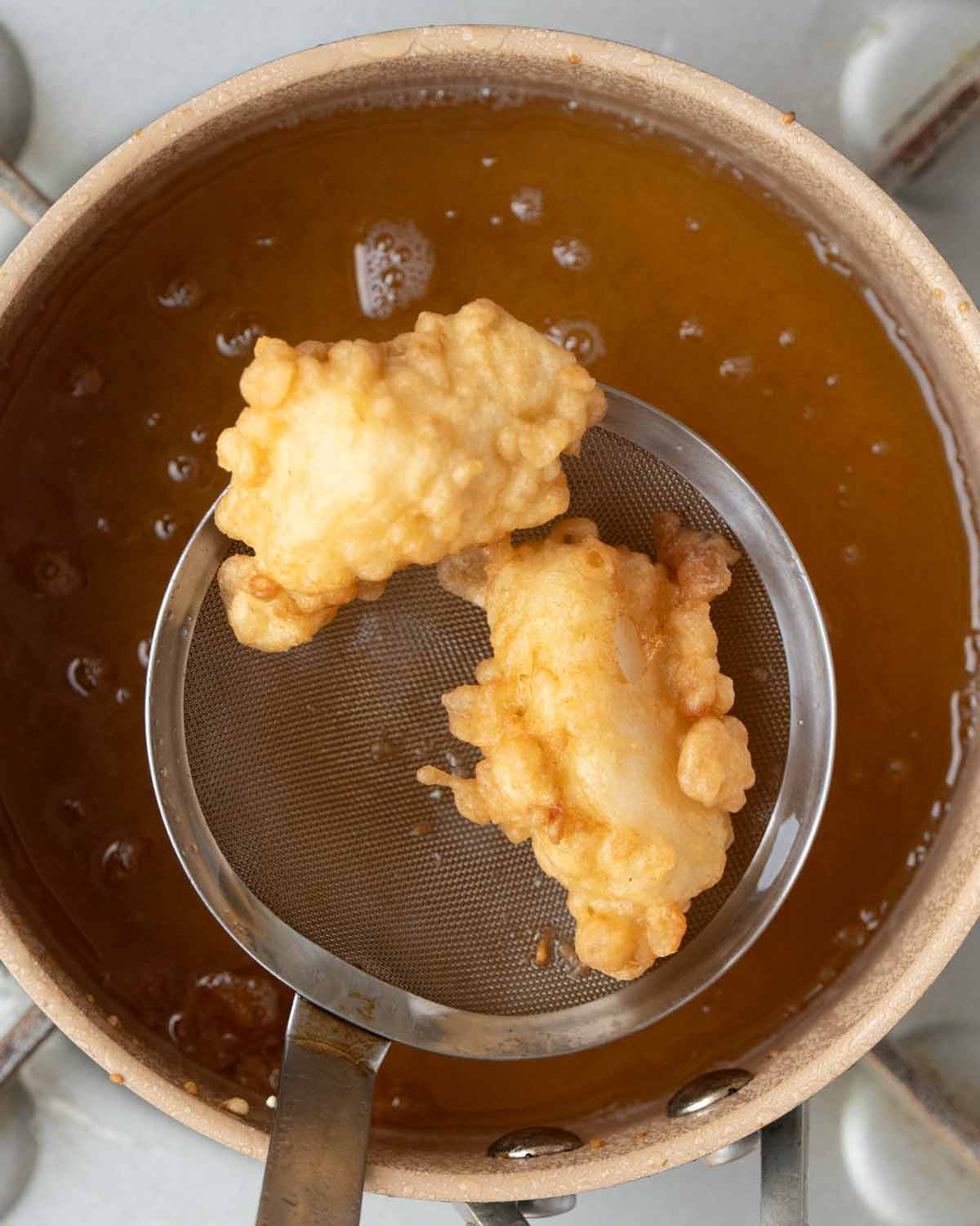 Fried golden tempura fish in the frying oil pot.