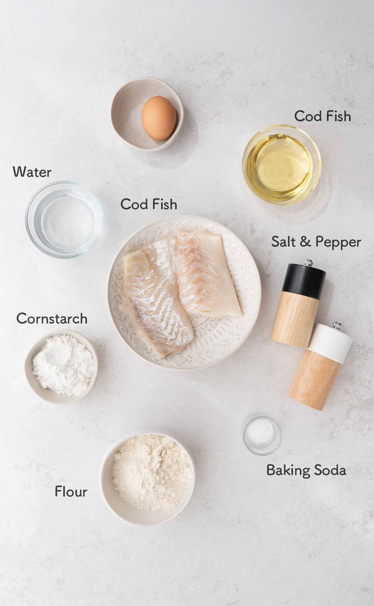 Labelled ingredients of making tempura fish displayed on the white table.