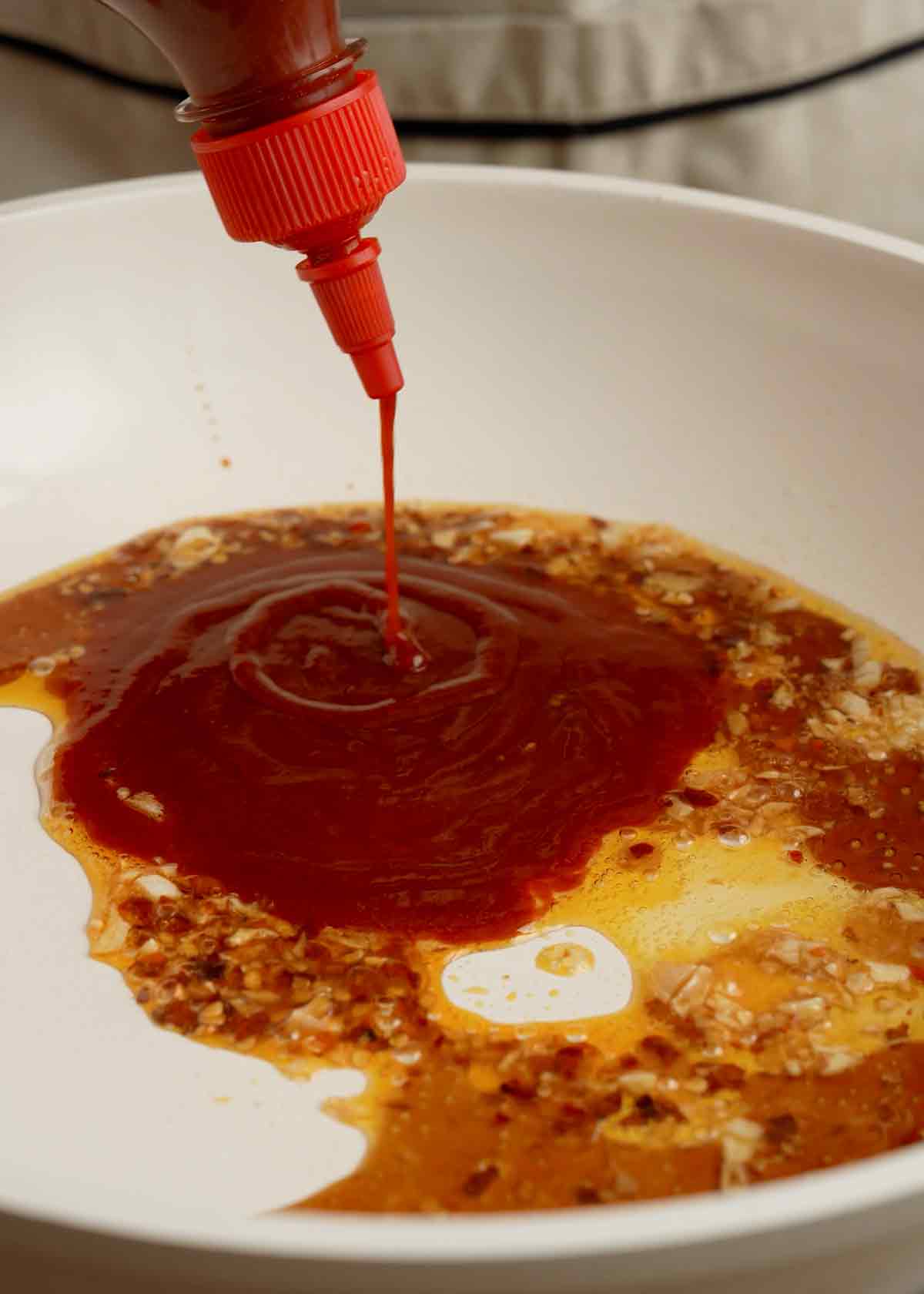 An image showing how to prepare hot honey sauce in a white saucepan.