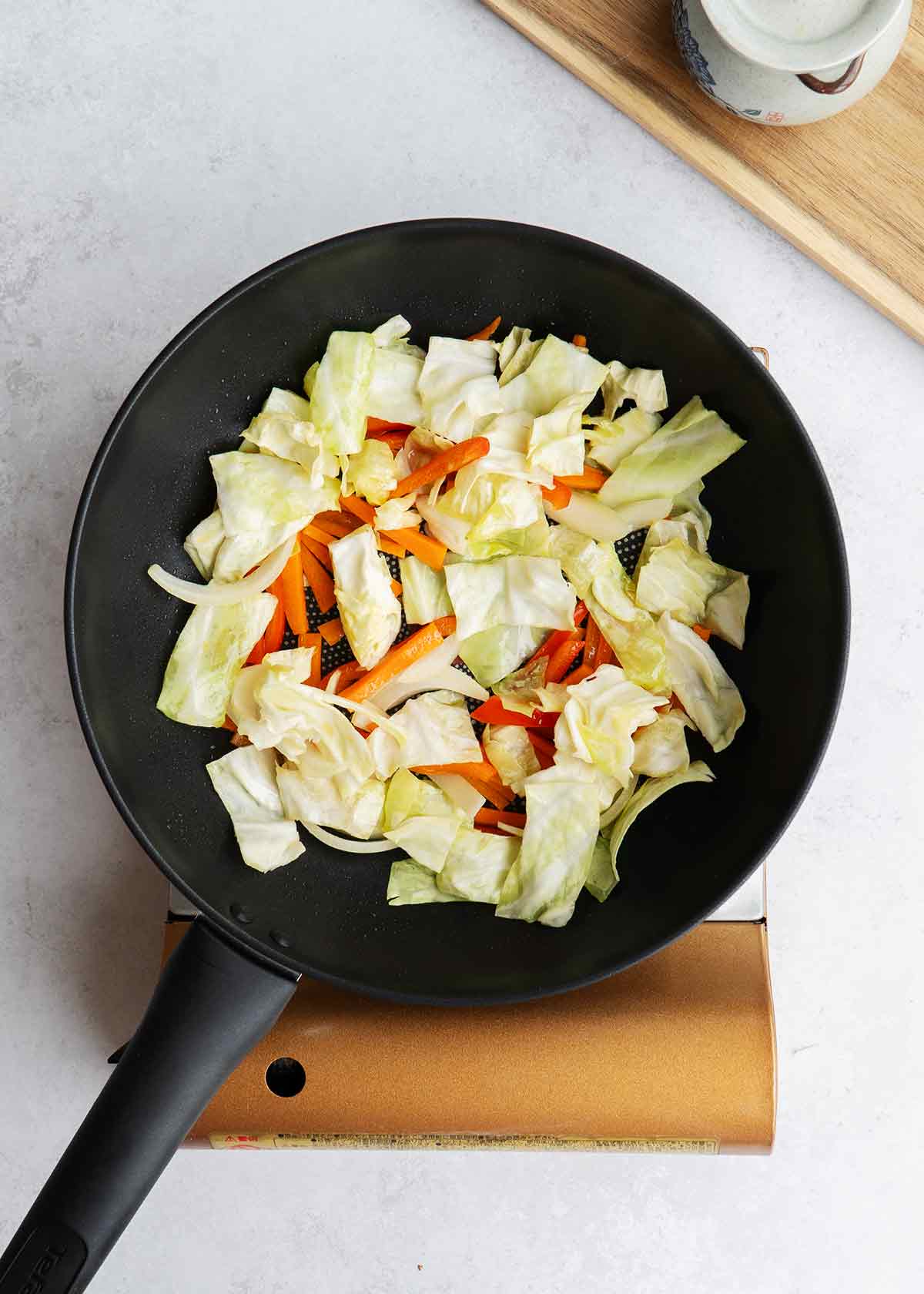 A large black wok containing stir fried mix vegetables.
