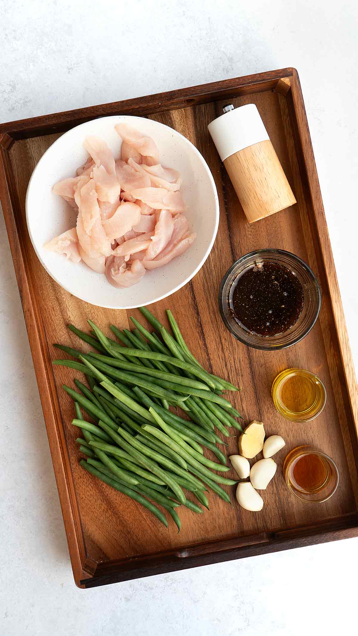 Labelled ingredients of making stir fried green beans and chicken, displayed on the wooden tray.