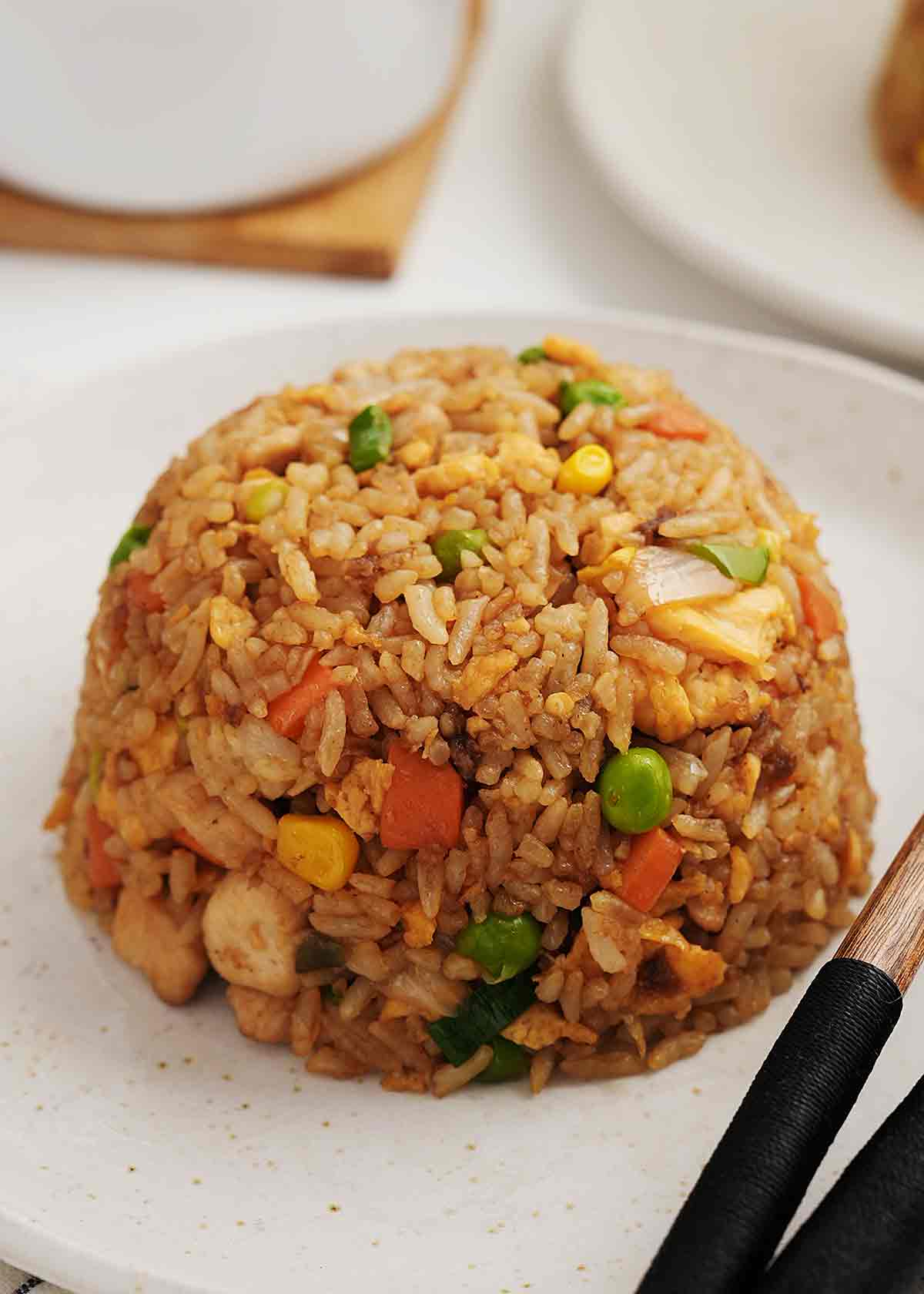 Upside down a bowl of fried rice with chicken and small vegetable cubes.