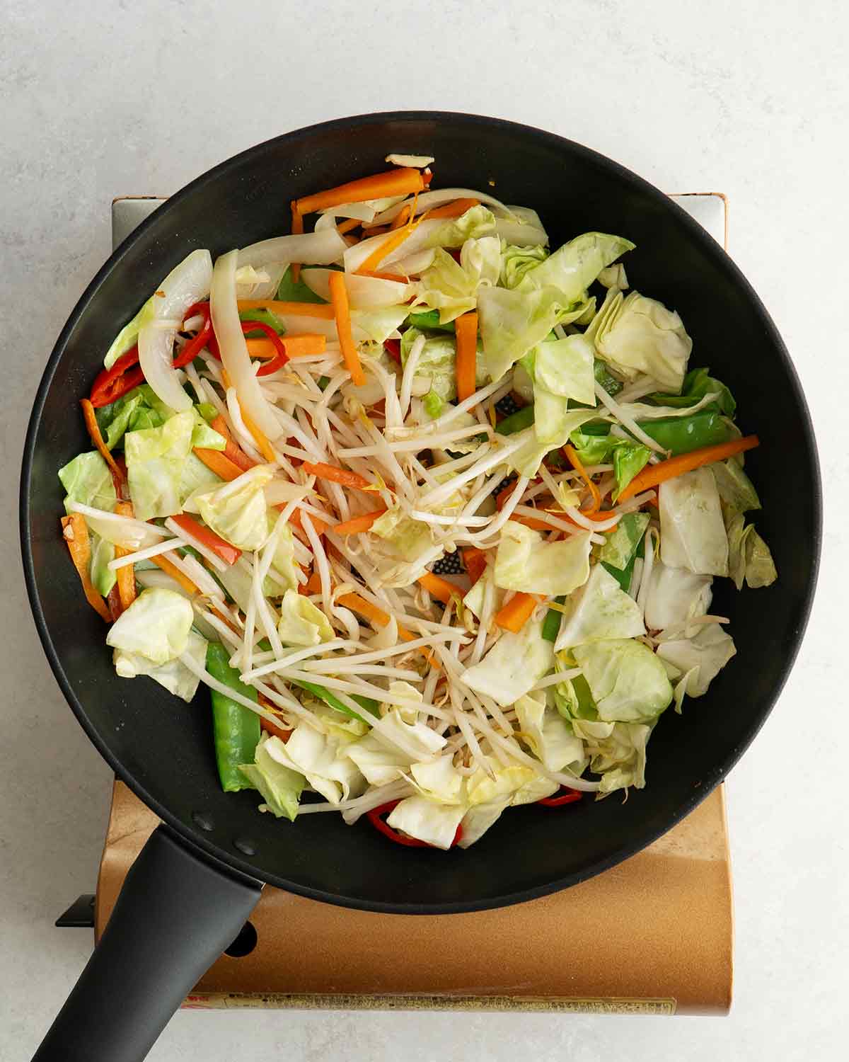 An image showing how to stir fry mix vegetables in a large wok.