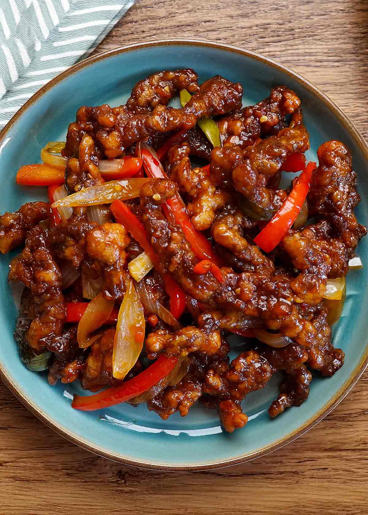 Crispy fried shredded chilli beef strips with red peppers displayed on the blue plate.