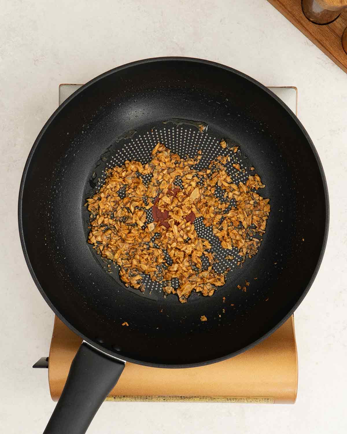 A black wok containing fried crispy golden minced garlic.