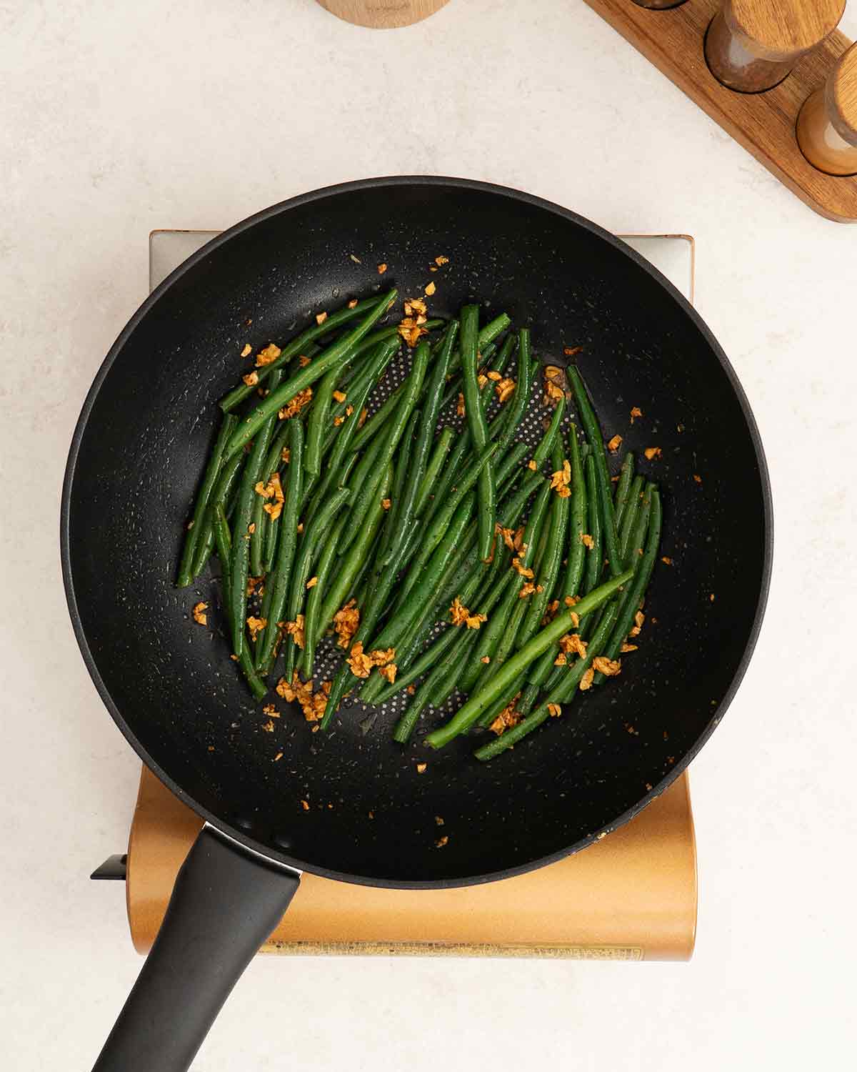 A large wok containing stir fried green beans with garlic.