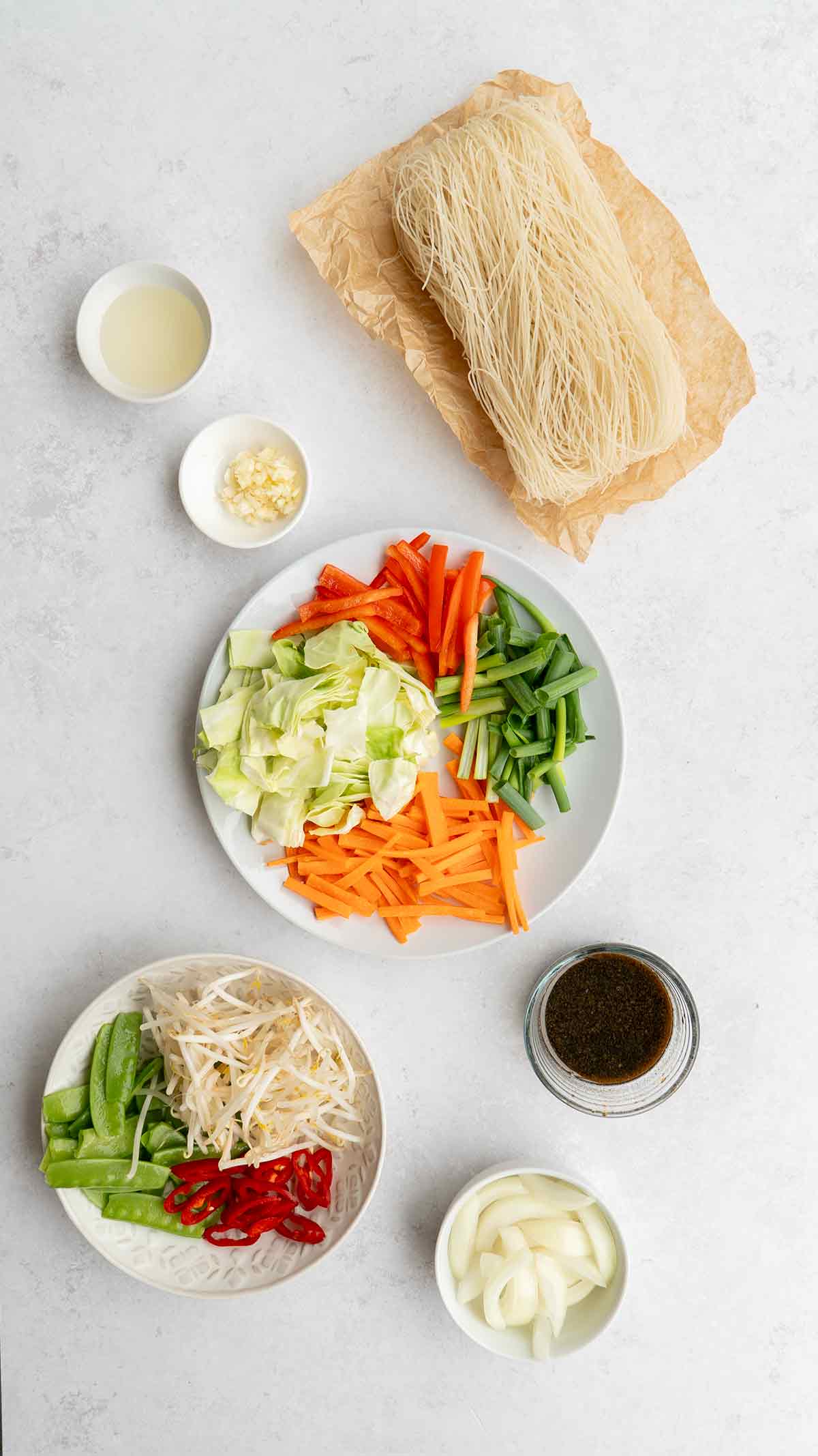 Labelled ingredients of making vegetable mei fun displayed on the white table.