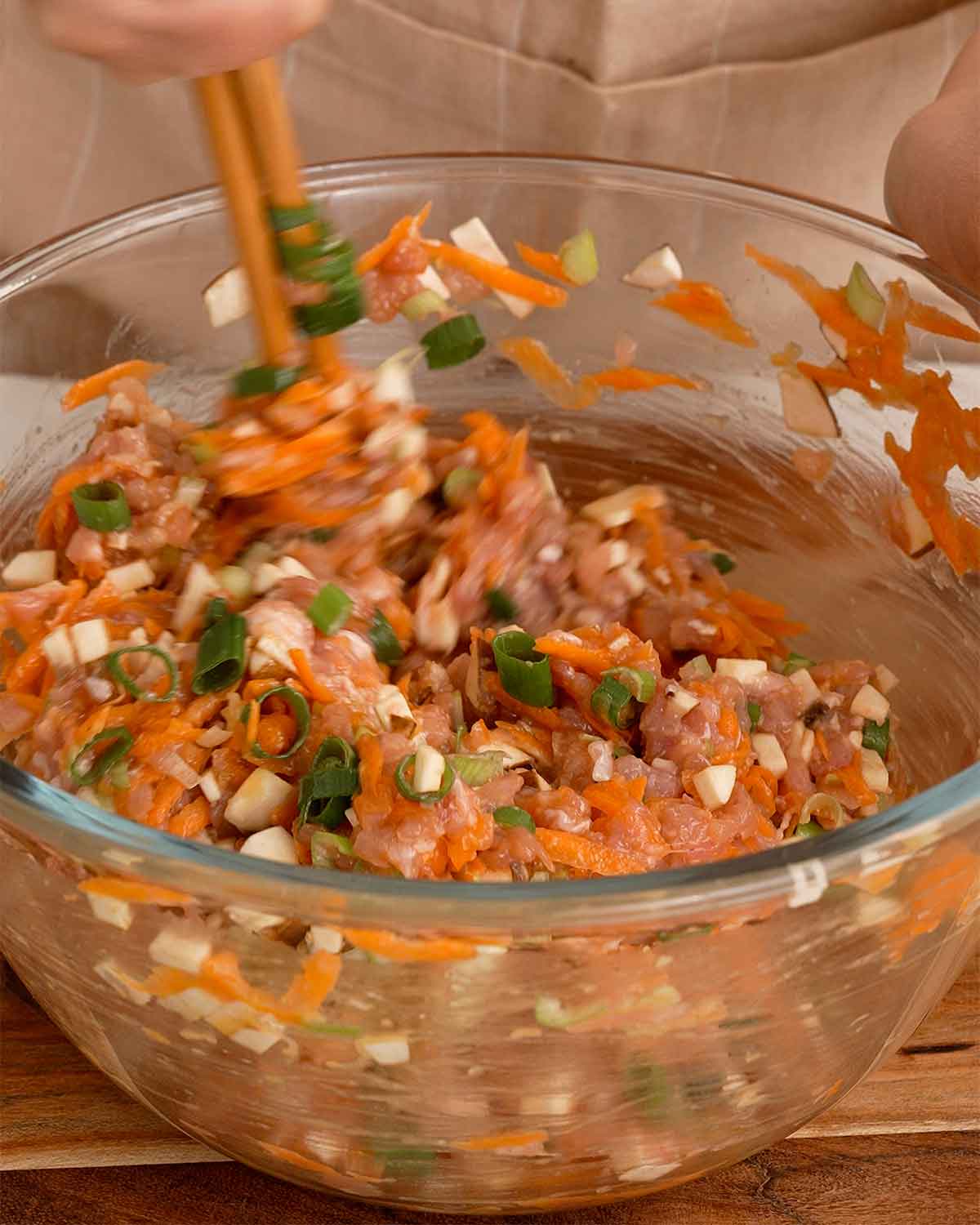 A transparent bowl containing chicken minced and vegetables fillings.