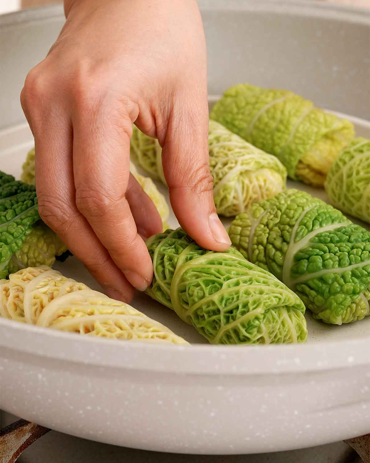 An image showing, placing the cabbage rolls inside a steamer plate.
