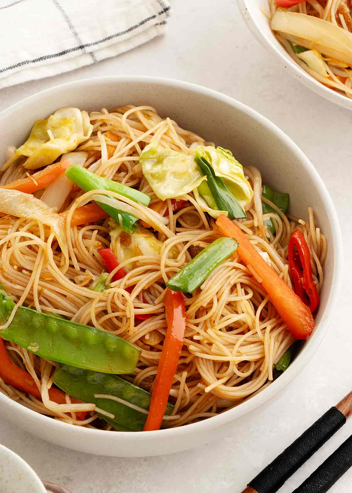 Stir fried mei fun noodles and vegetables displayed in a small bowl.