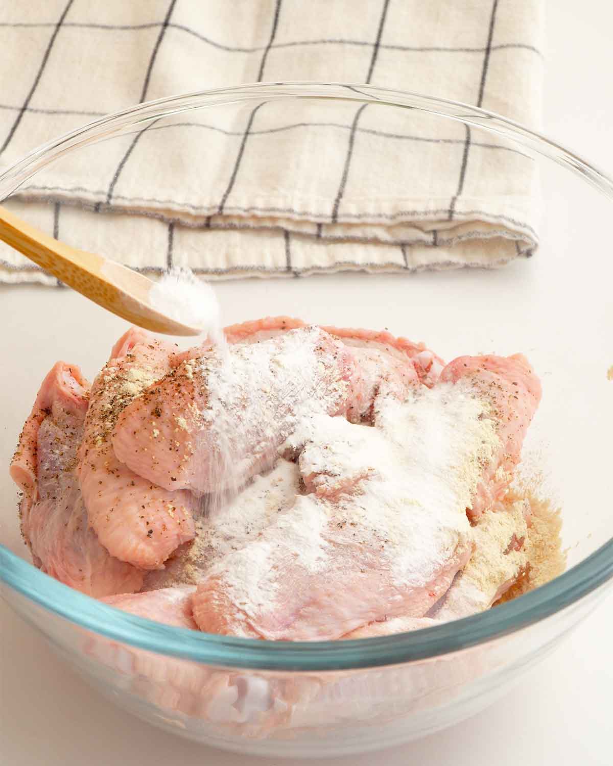 A large bowl containing chicken wings and seasoning ingredients.