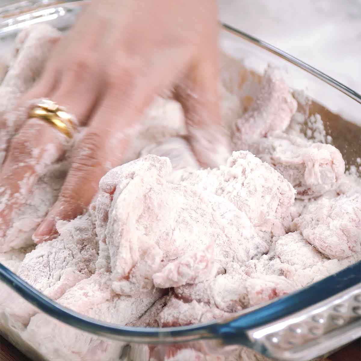 A large tray containing chicken wings coated with flour.