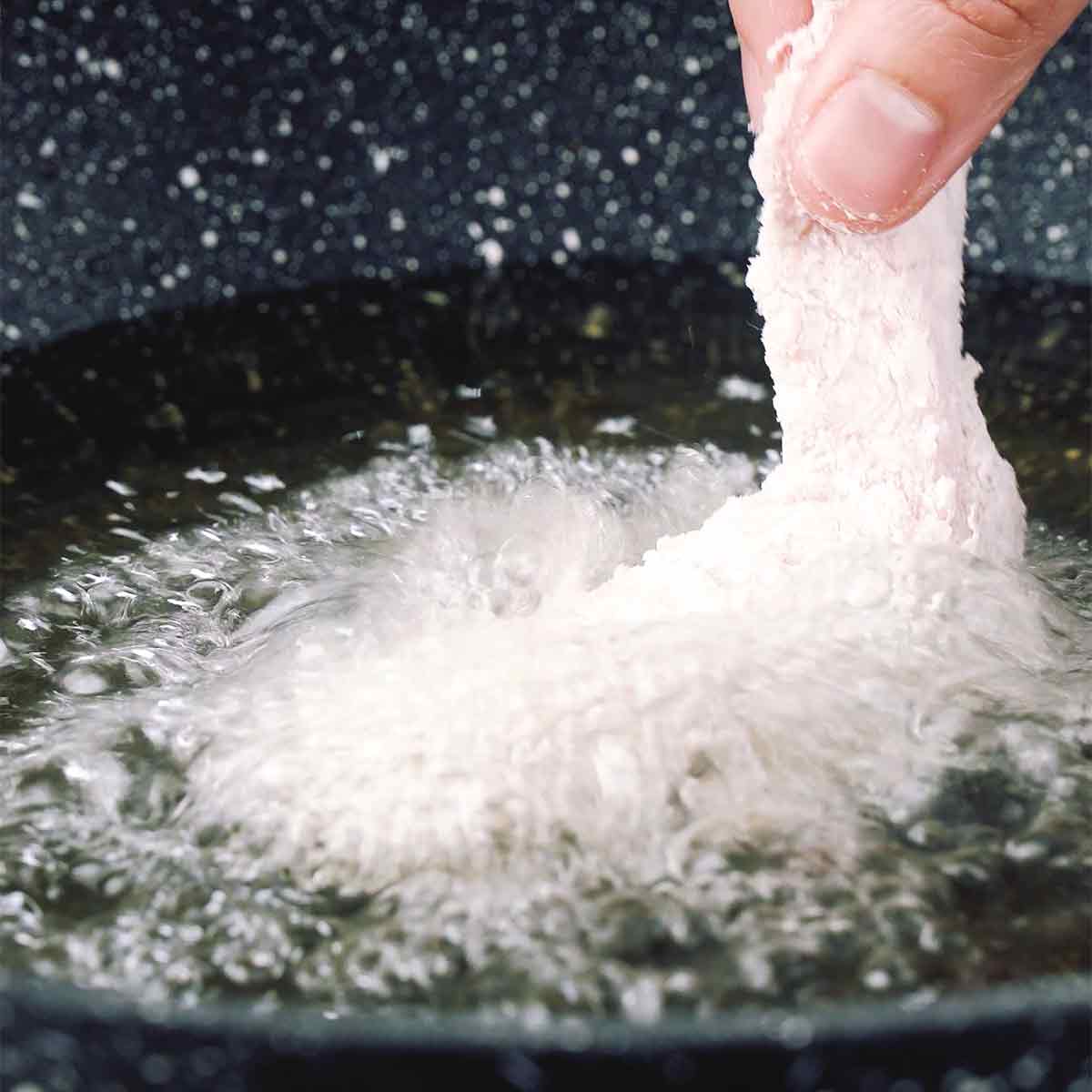A picture showing adding chicken wings into the hot oil.