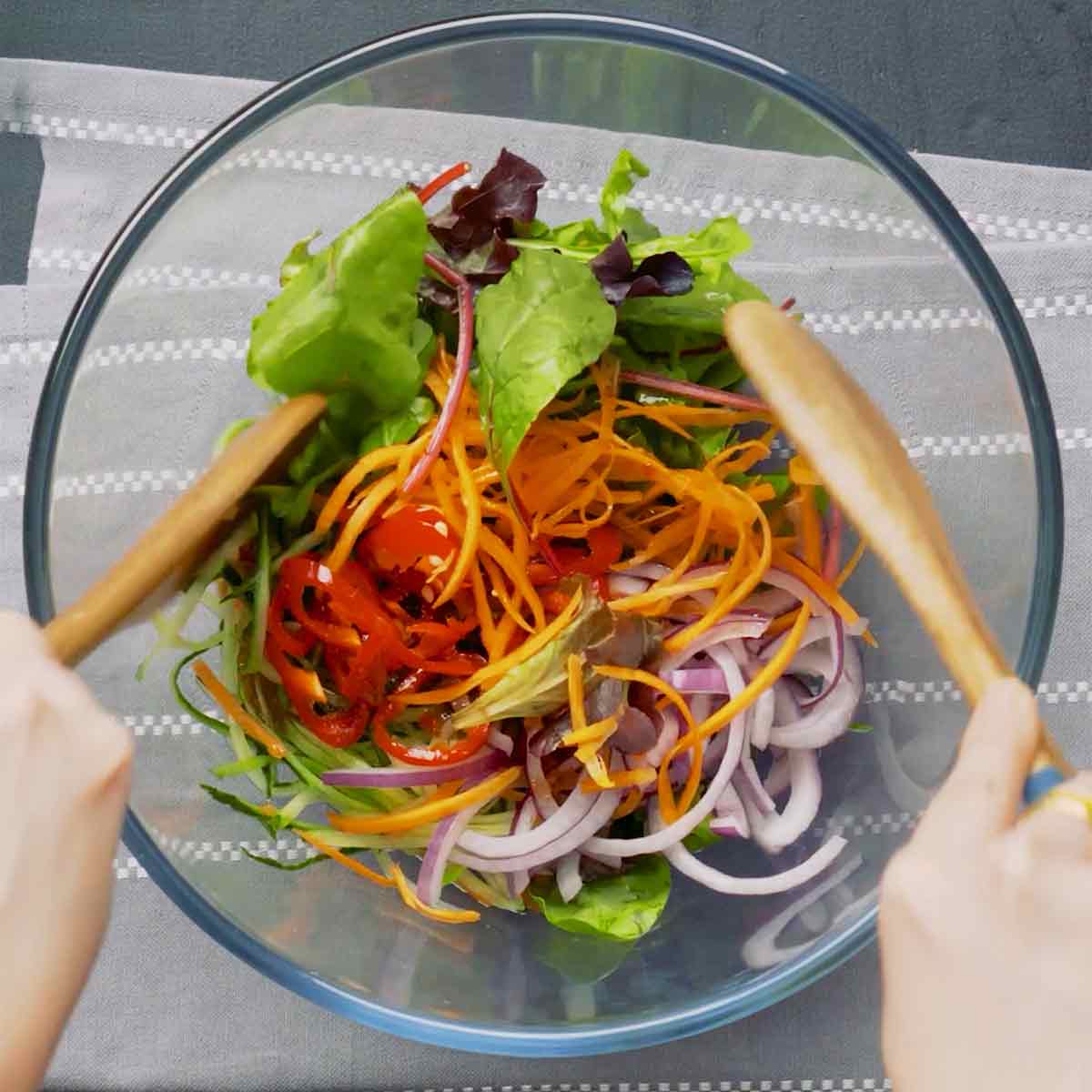 A transparent bowl containing mixed salad vegetables.