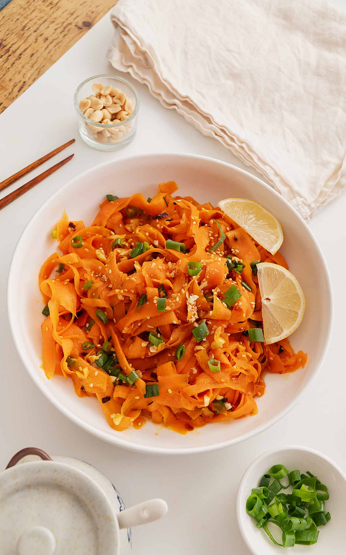 A small bowl containing carrot salad with lemon wedges on the side.