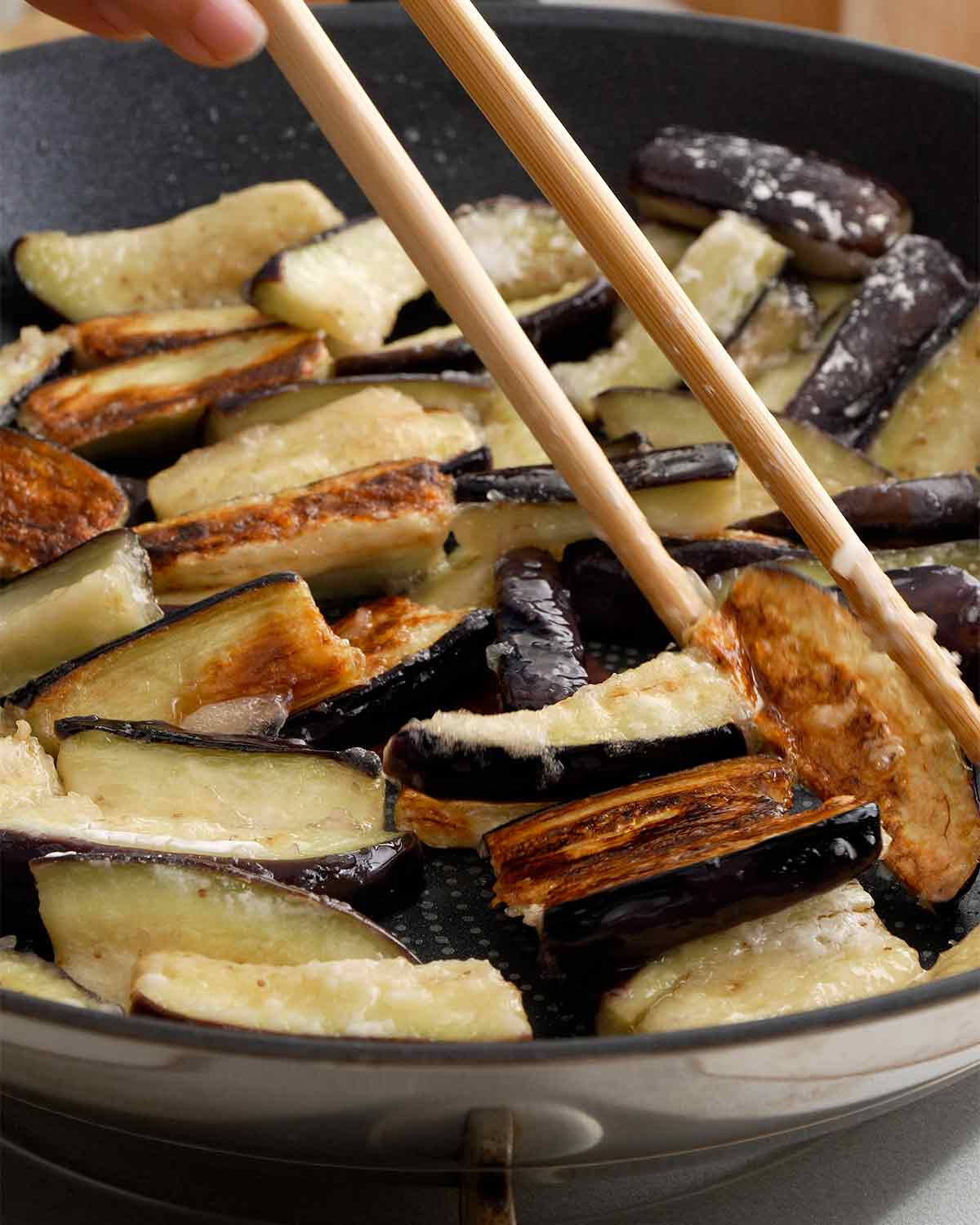 Pan frying the aubergine in the black non-stick pan.
