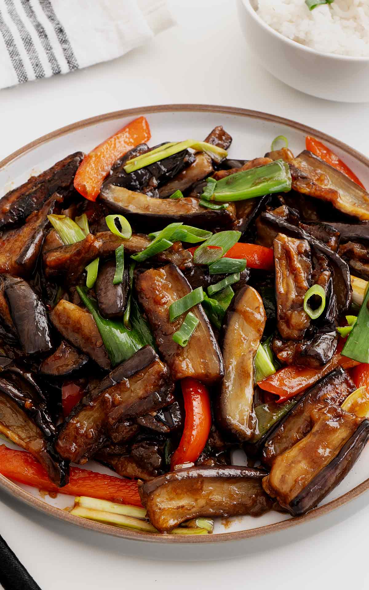 Stir fried aubergine and vegetables displayed on the white plate.