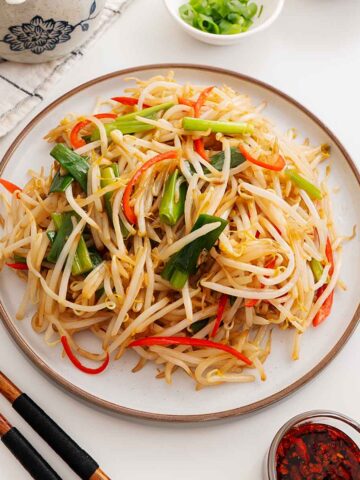 An image of a bean sprout stir fry dish displayed on a white plate.
