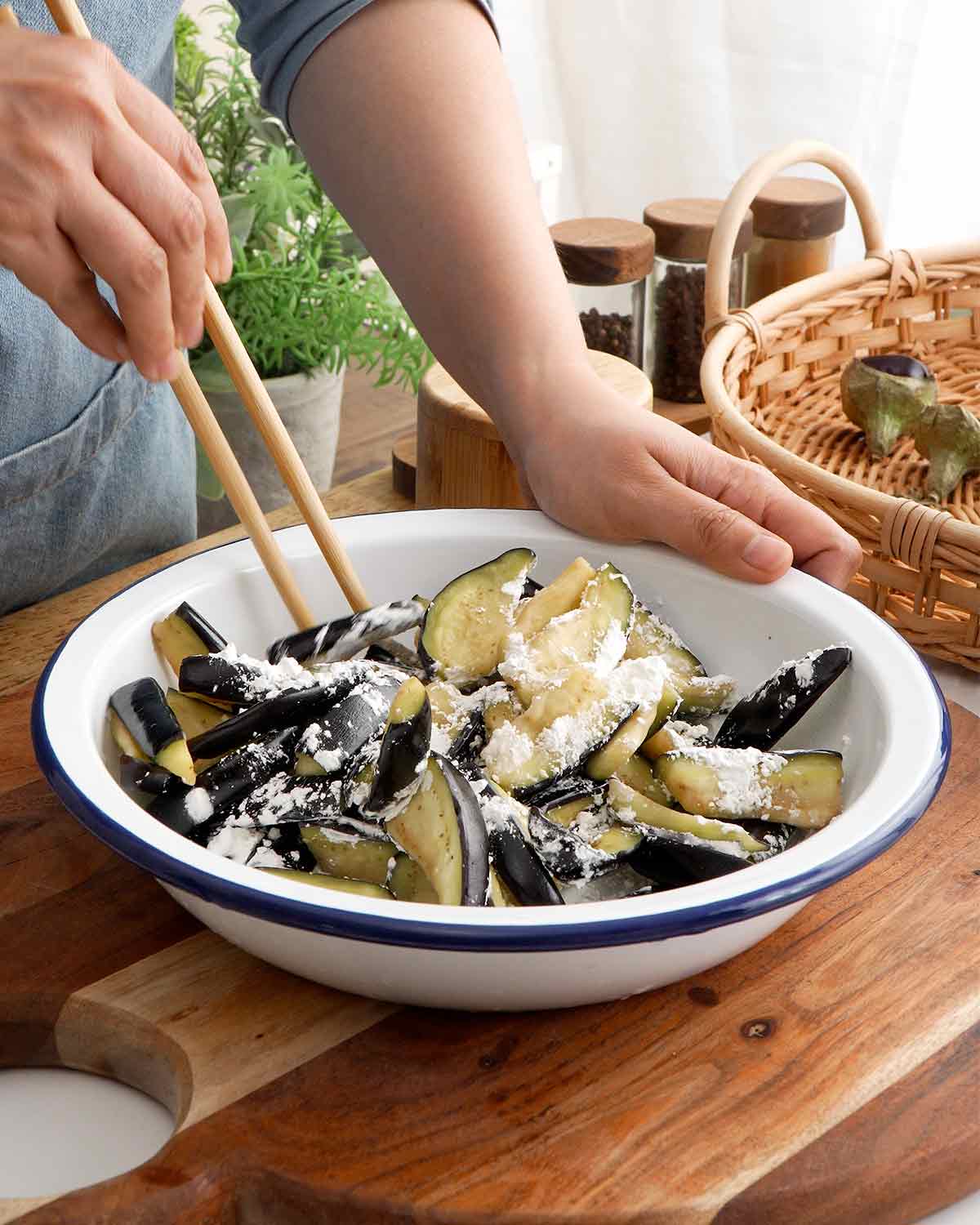 An image showing how to coat the aubergine slices with cornstarch.