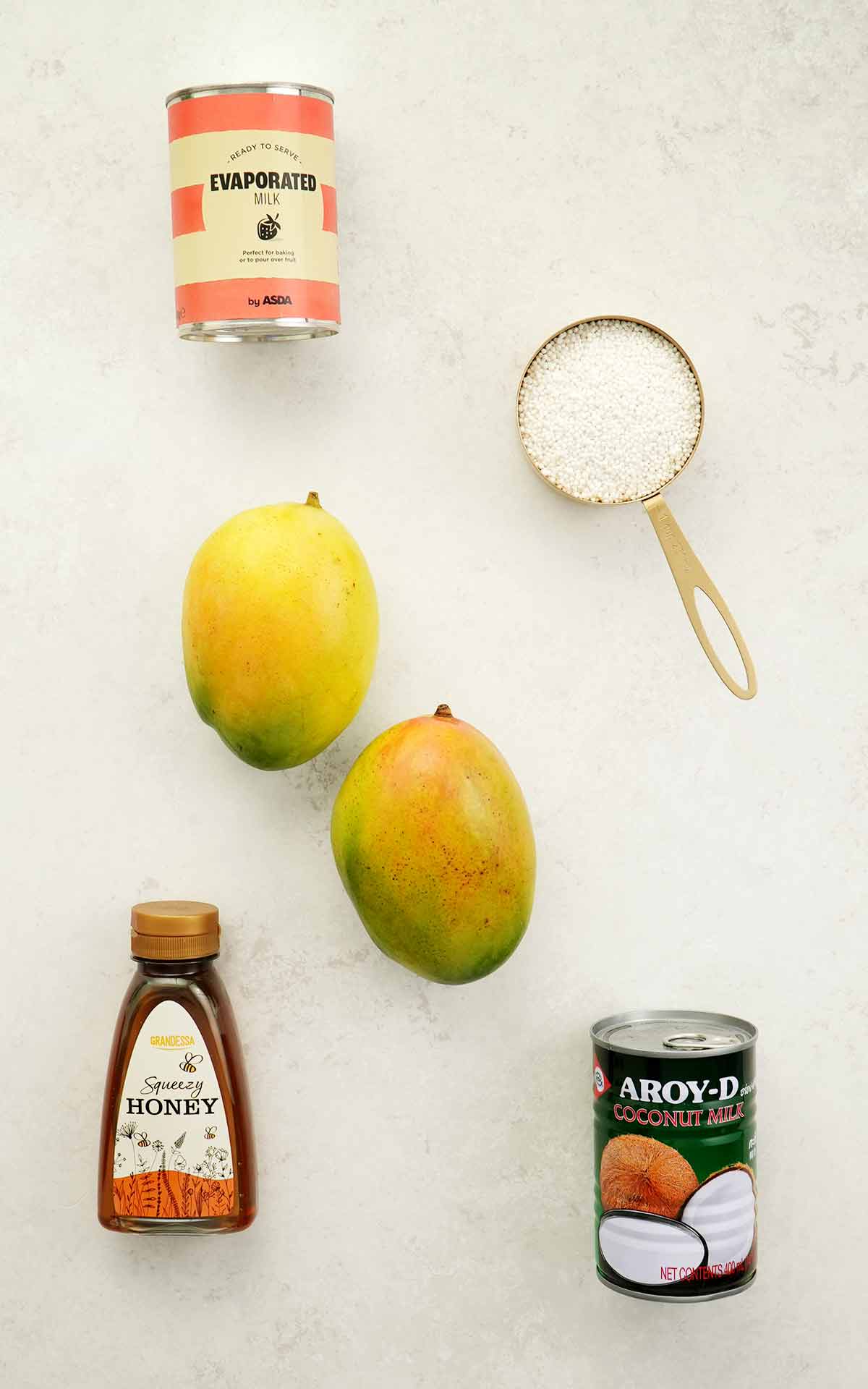 Labelled ingredients of making sago and mango dessert displayed on the white table.