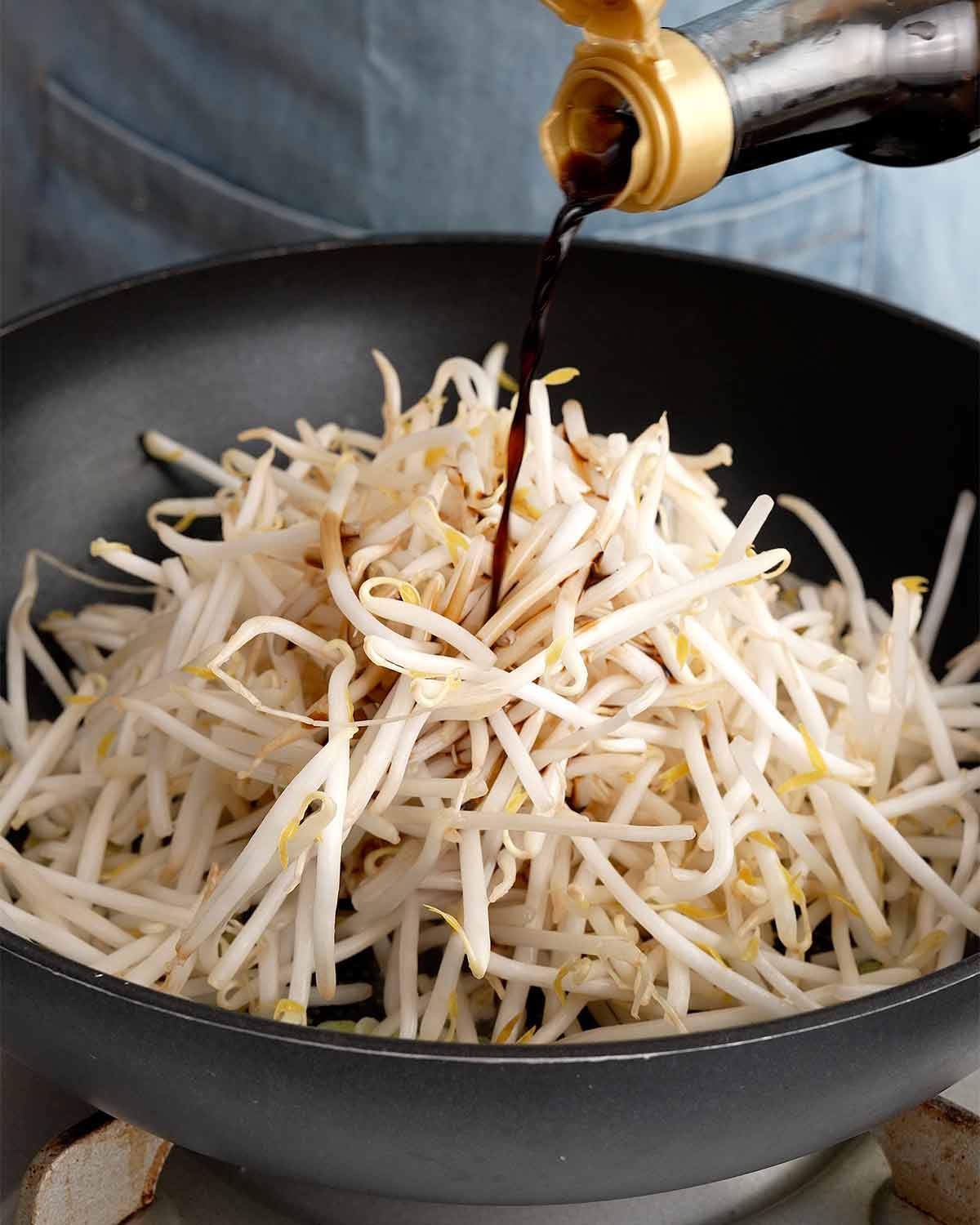 An image showing adding seasonings to the beansprouts.