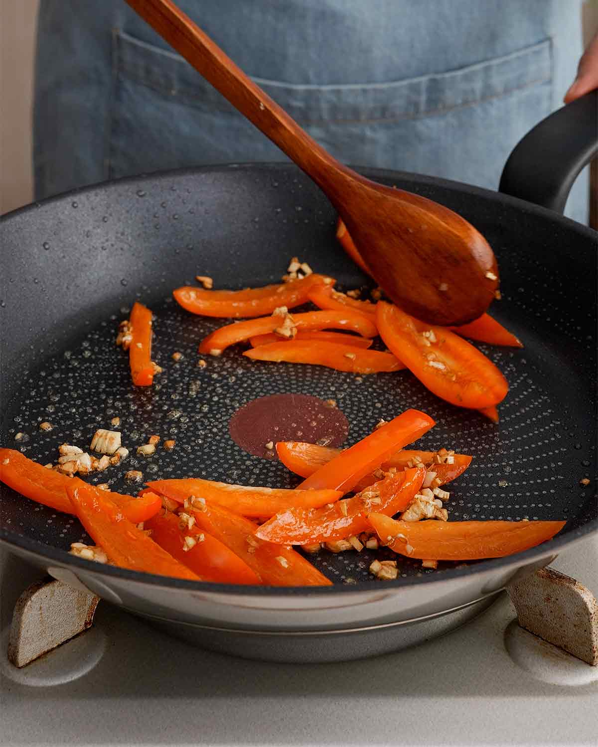 A black pan containing minced garlic and red bell peppers.