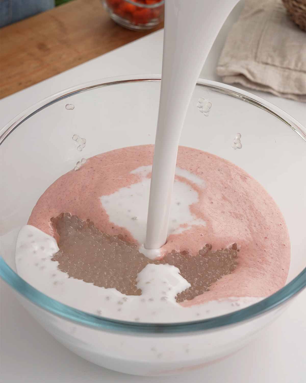 A large mixing bowl containing a mixture of strawberry, sago, coconut milk and evaporated milk.