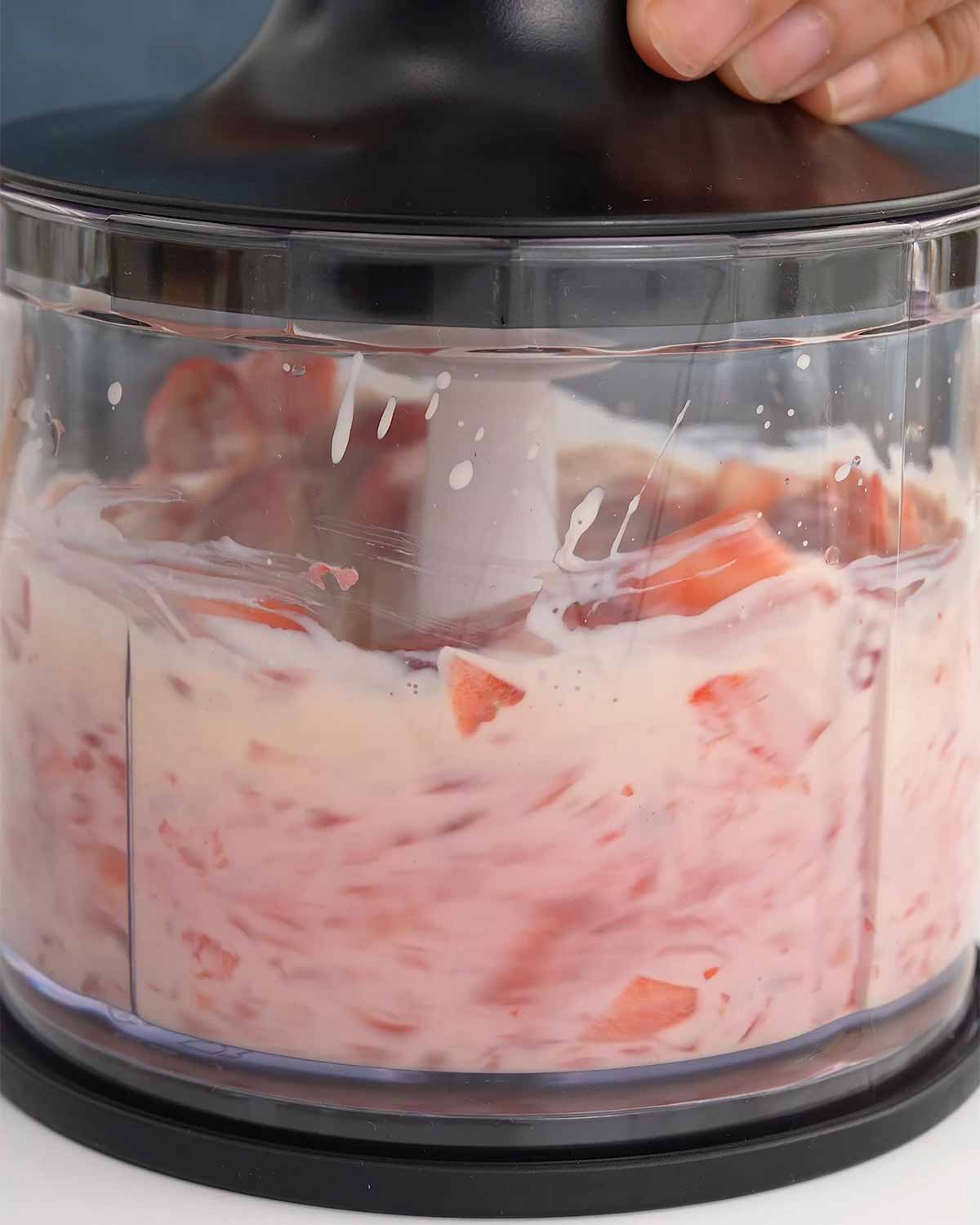 An image showing how to blend strawberries in a food blender.