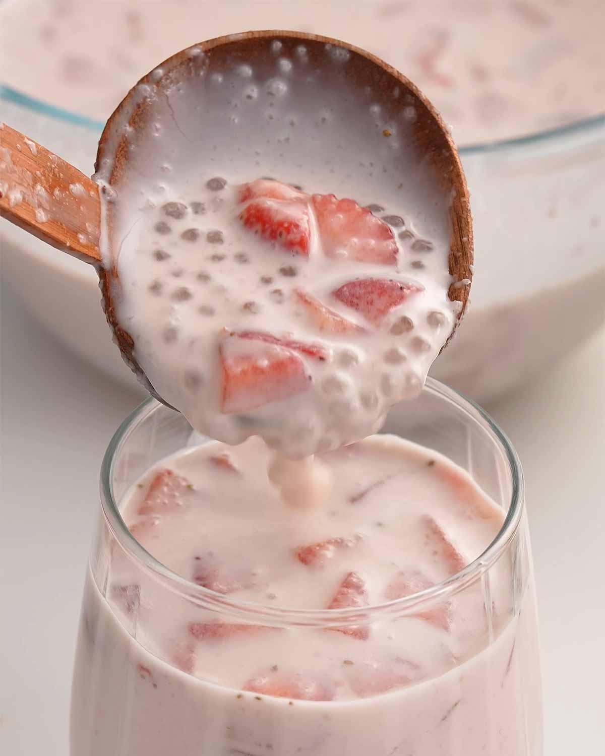 An image showing pouring sago drink with strawberry chunks into the drinking glass.