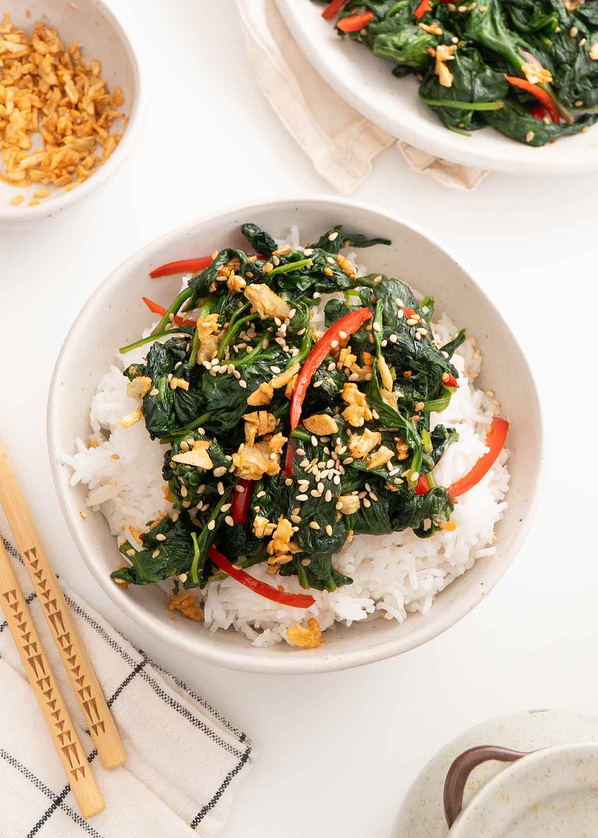 A white bowl containing rice and fried spinach with chillies and garlic.